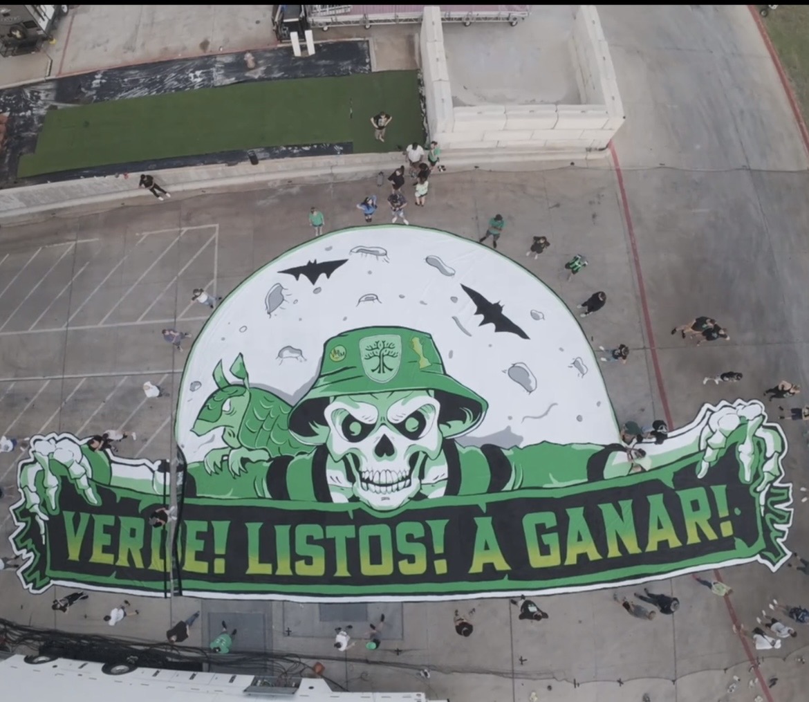 Large banner with a skull wearing a green hat, holding a green banner with text, in an outdoor area.