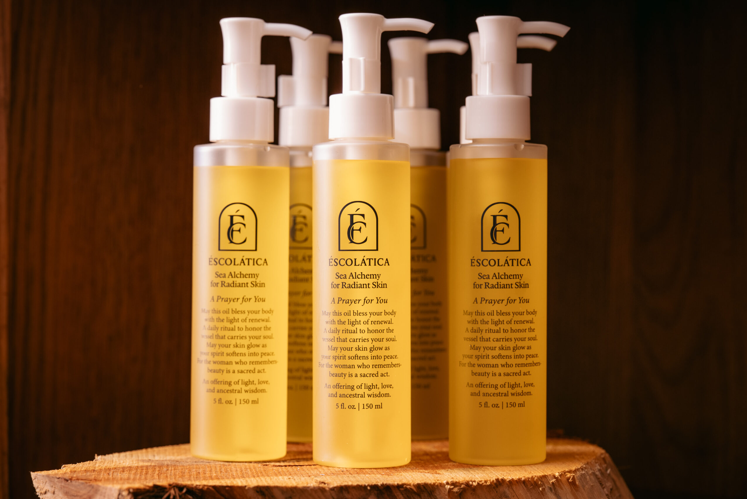 Three yellow bottles with white pump dispensers on a wooden surface against a dark background.