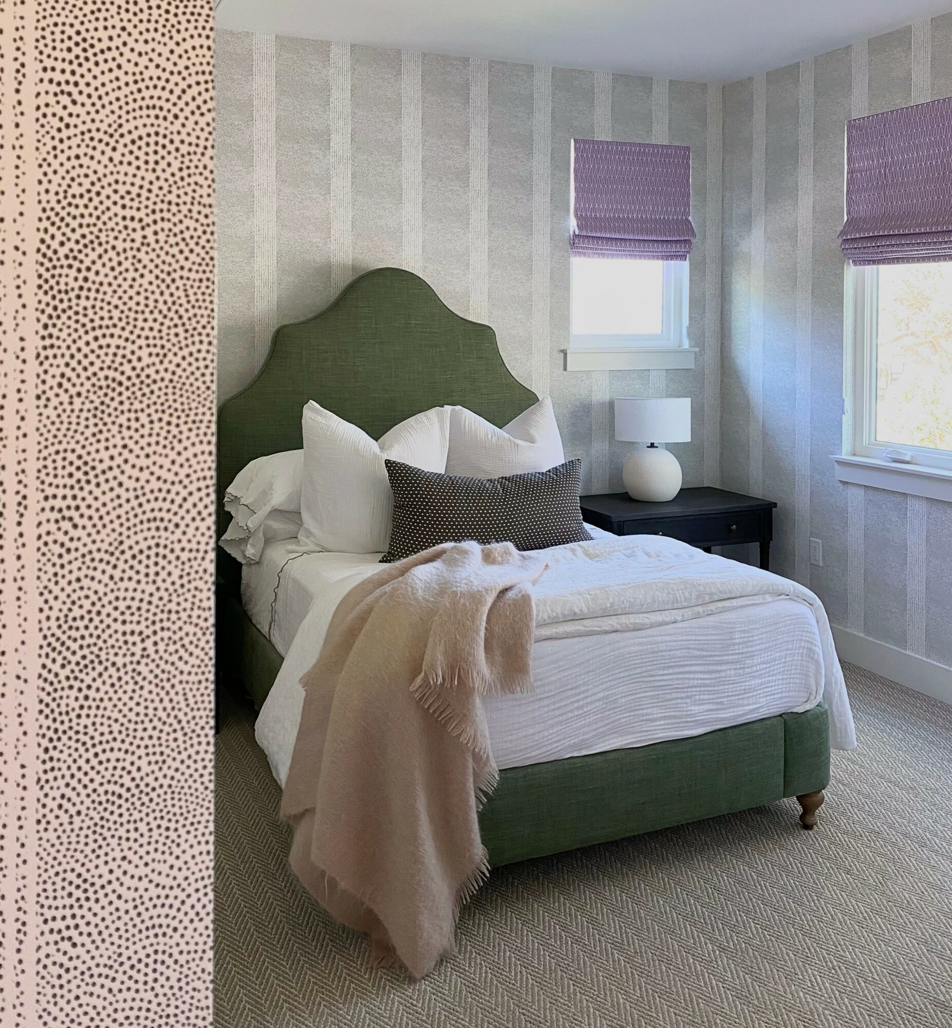 Bedroom with a bed, green headboard, white bedding, and two windows with purple blinds.