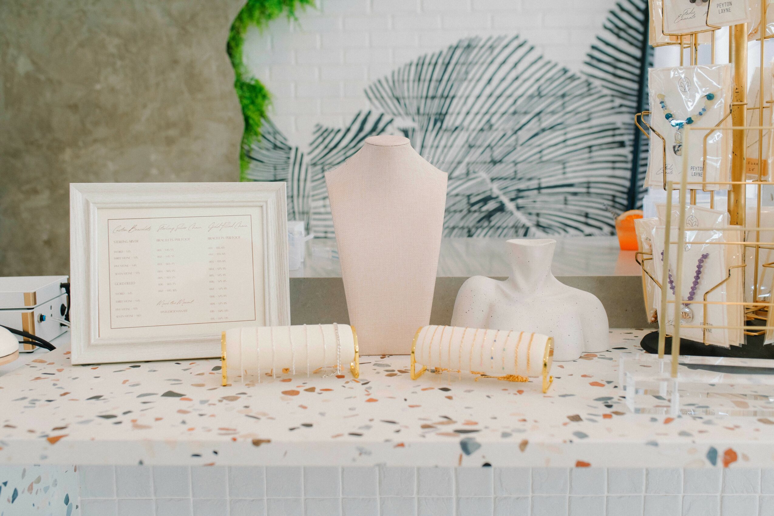 Decorative table with vases, framed picture, and art supplies, against a textured wall with green plant accents.