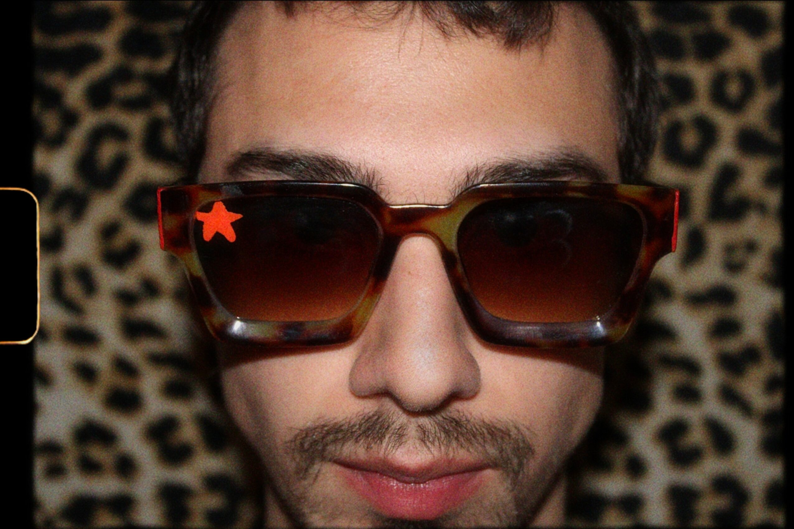 Close-up of a person wearing large sunglasses with a leopard print background.