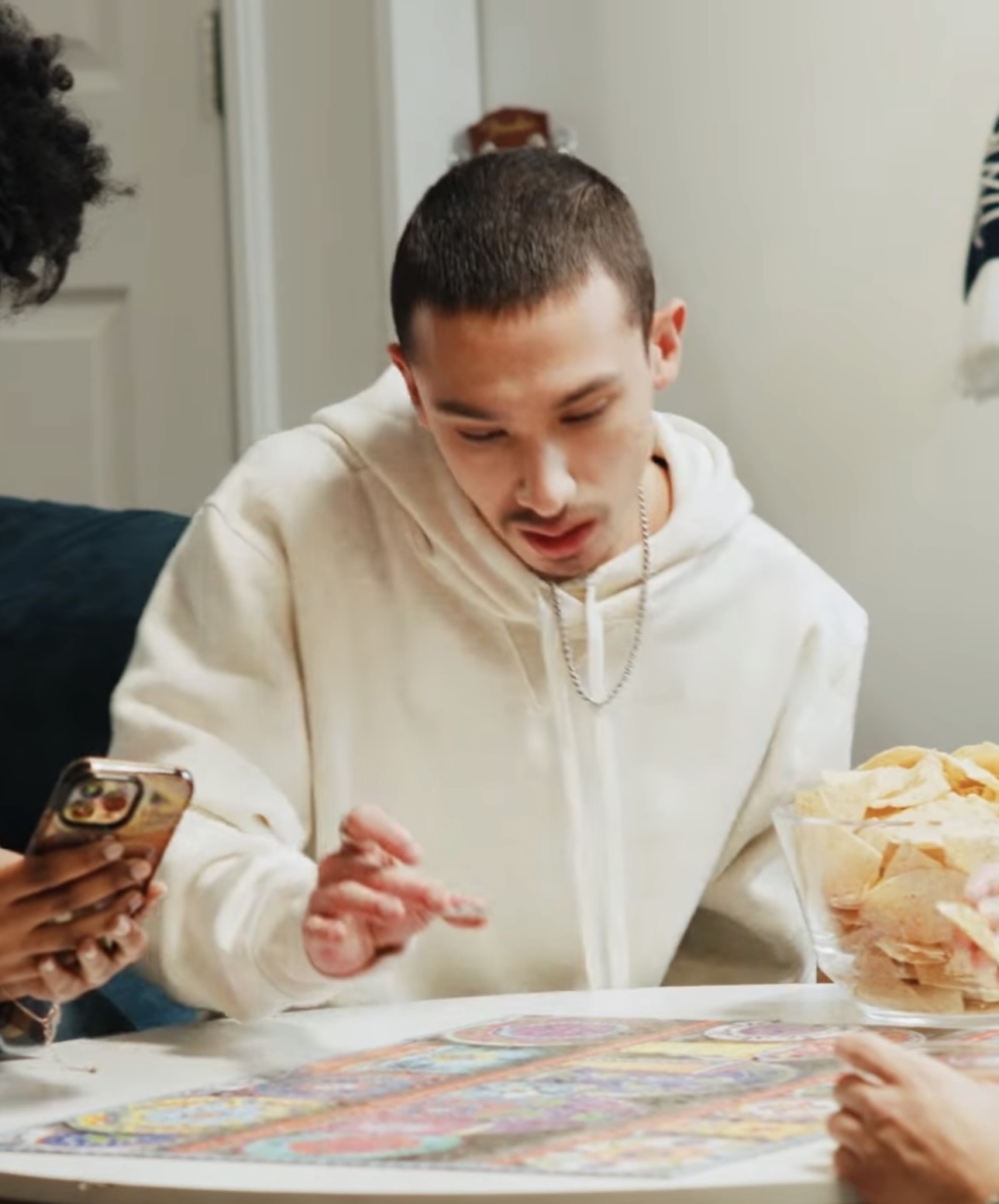 Young person with short hair wearing a white hoodie looking at a colorful map on a table.