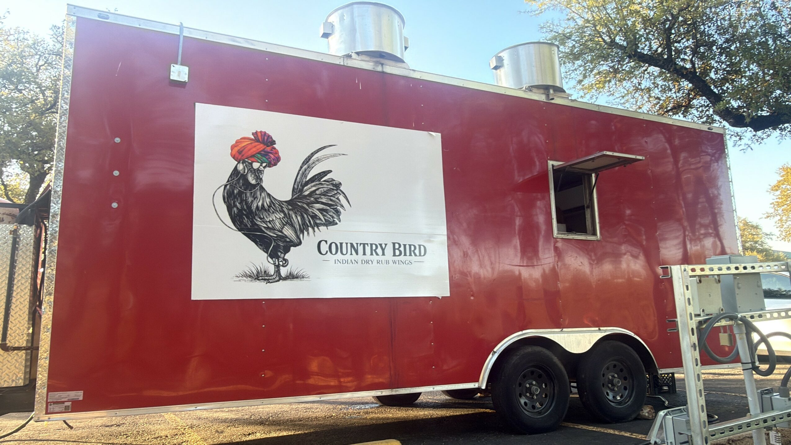 Red food truck with a large sign of a black rooster and the text 'Country Bird' on the side.