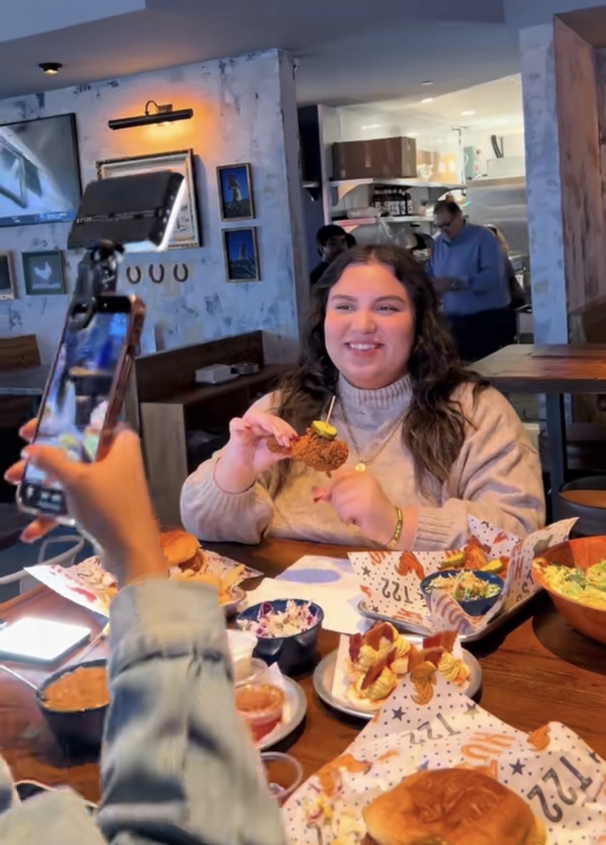 Young woman smiling at a birthday celebration with food and decorations in a restaurant.