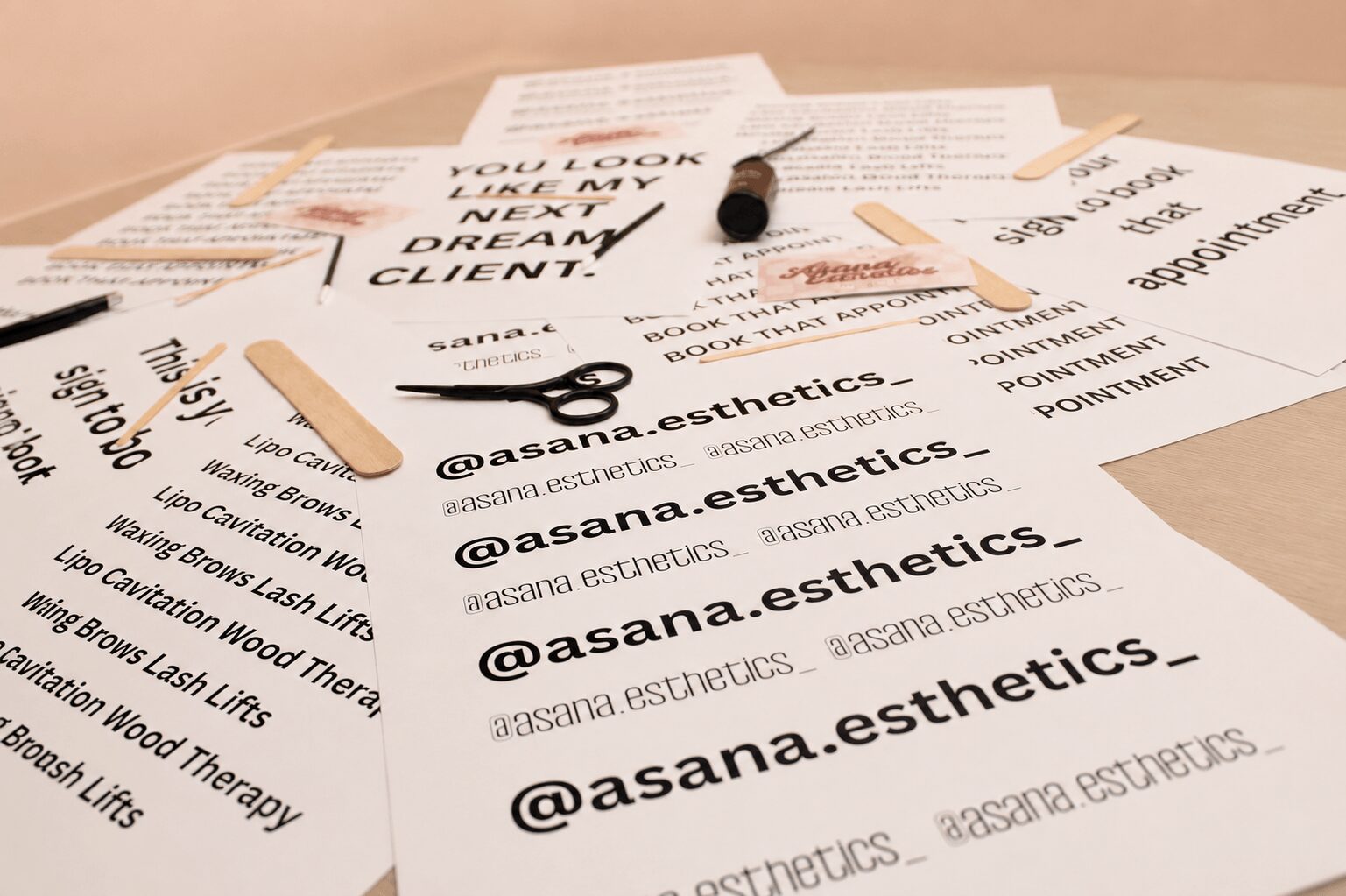 Multiple printed sheets of paper, a pen, and a wooden stick on a beige surface.