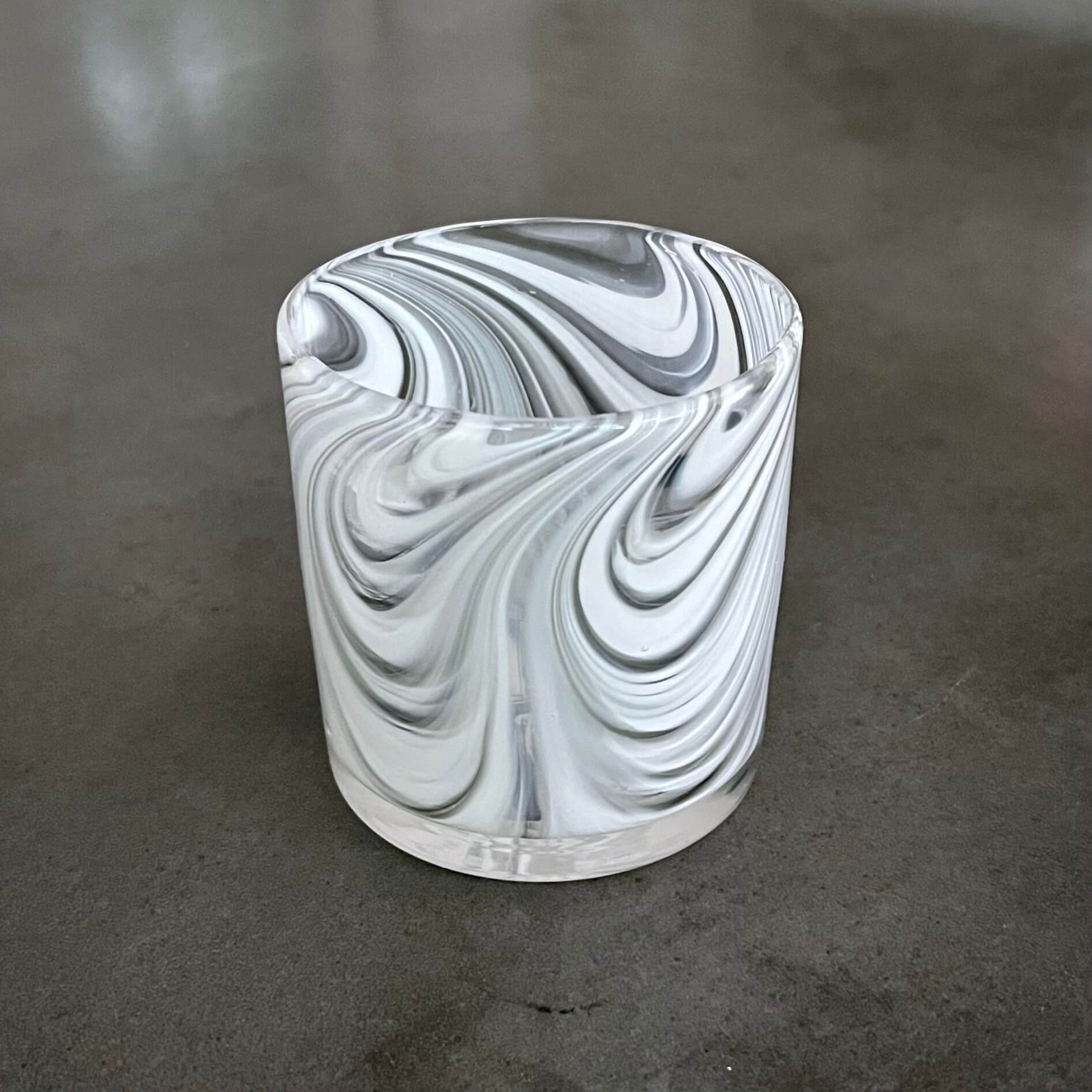Marbled cylindrical object with black, white, and gray swirls on a gray surface.