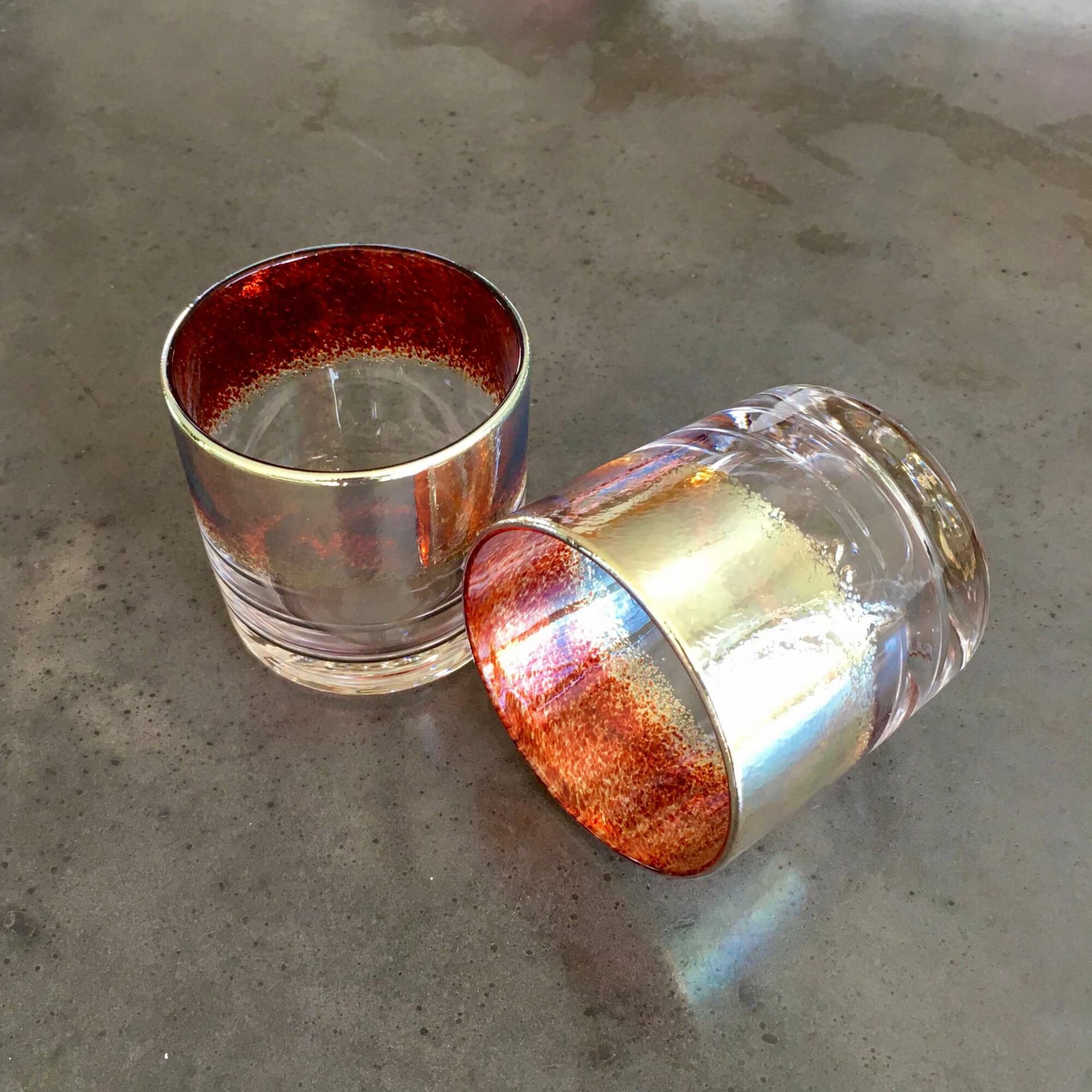 Two glass cups, one upright and one on its side, on a gray surface.