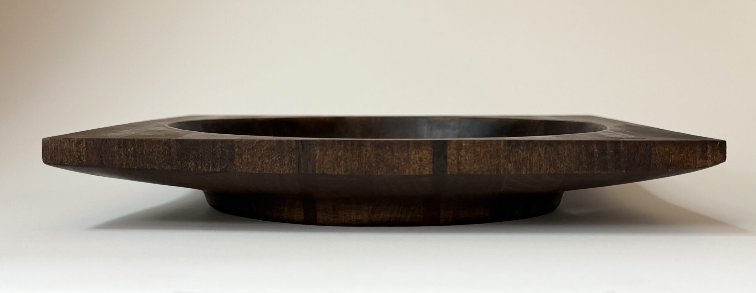 Round wooden tray with a raised edge, placed on a white surface against a plain background.