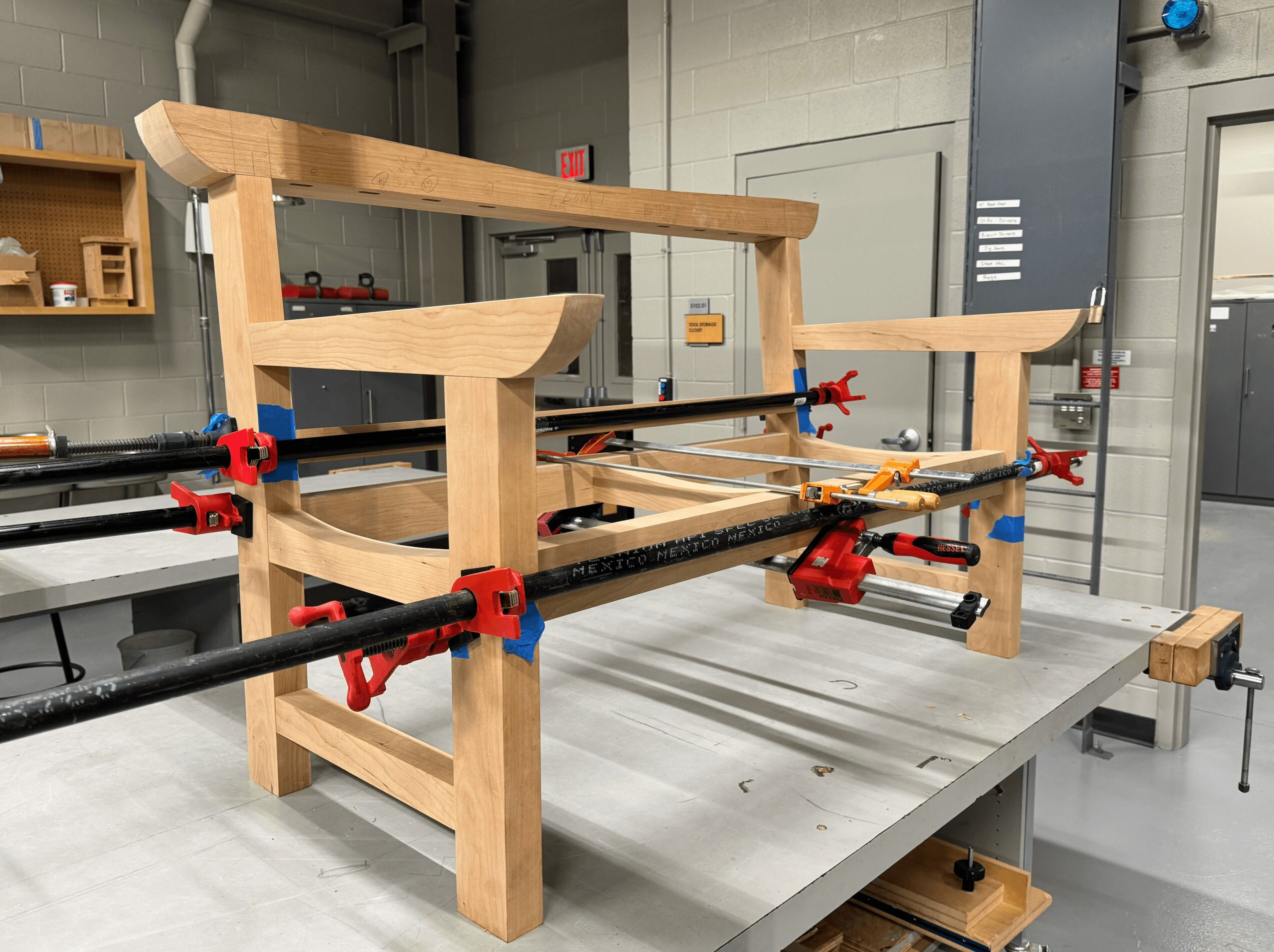 Wooden foosball table with red and blue players on a metal workbench in workshop.