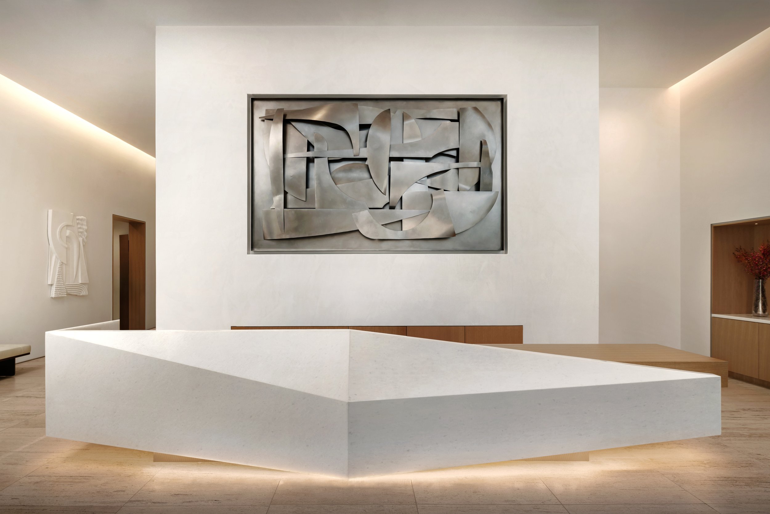 Modern art piece on a white wall in a minimalist room with a white reception desk, wooden flooring, and subtle lighting.