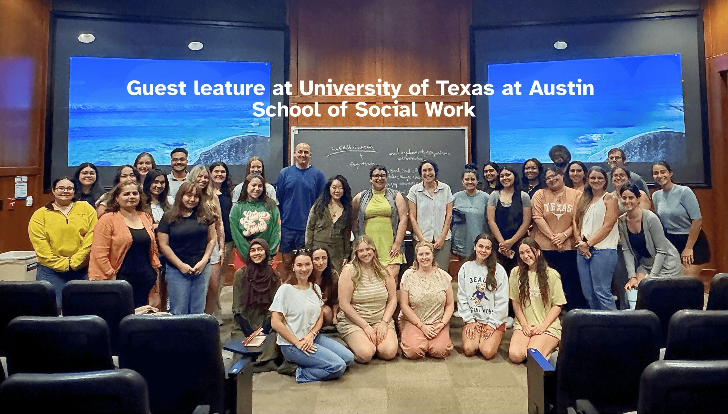Group of people posing in front of a presentation screen at University of Texas at Austin School of Social Work.