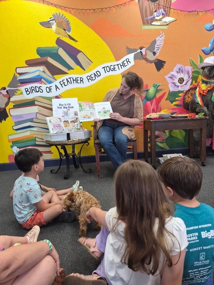 Adult reading a book to children in a colorful room with bird and book decorations, and a mural background.