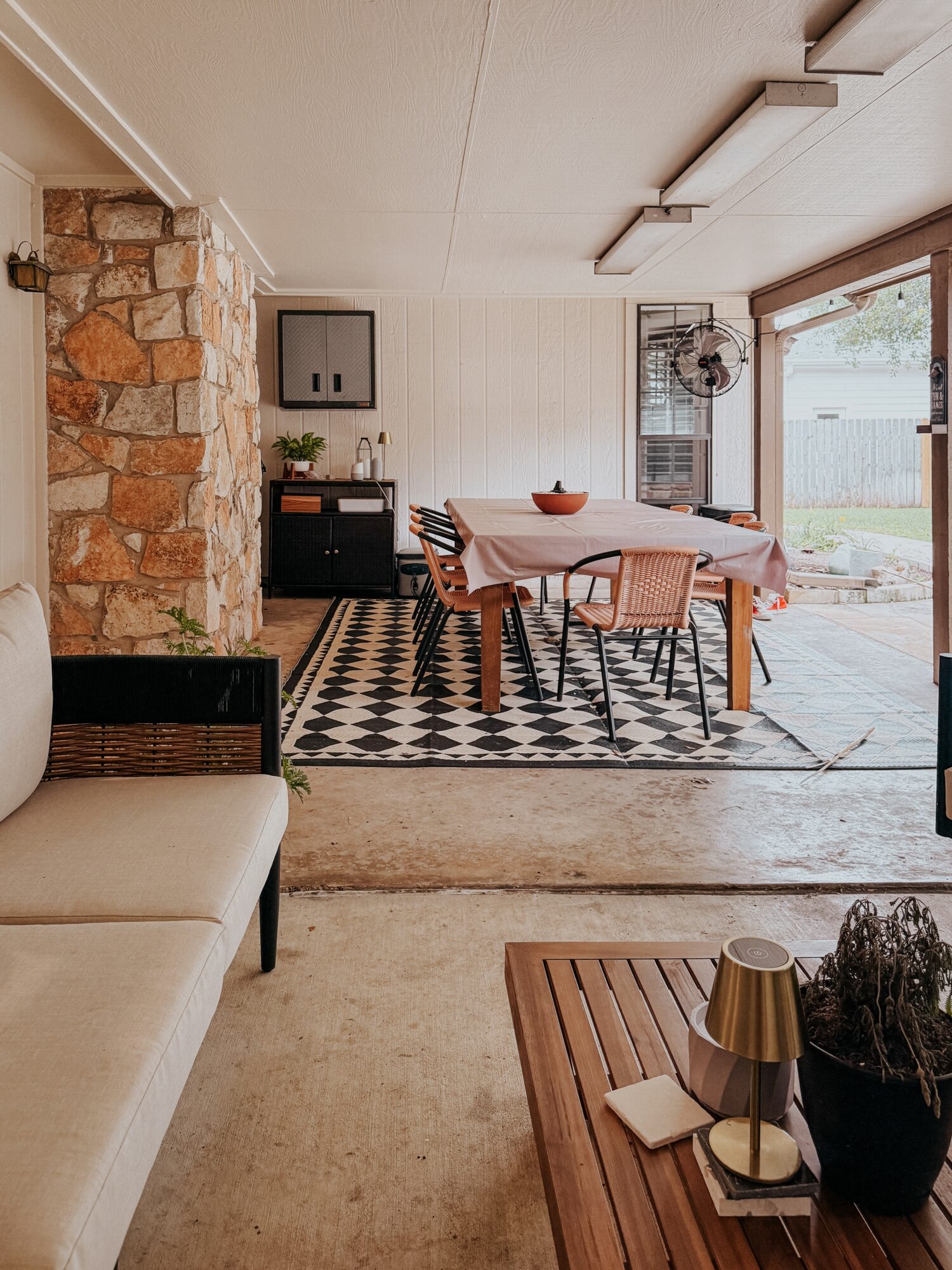 Dining area with a table, chairs, and a large window, adjacent to a stone wall and a patterned rug.