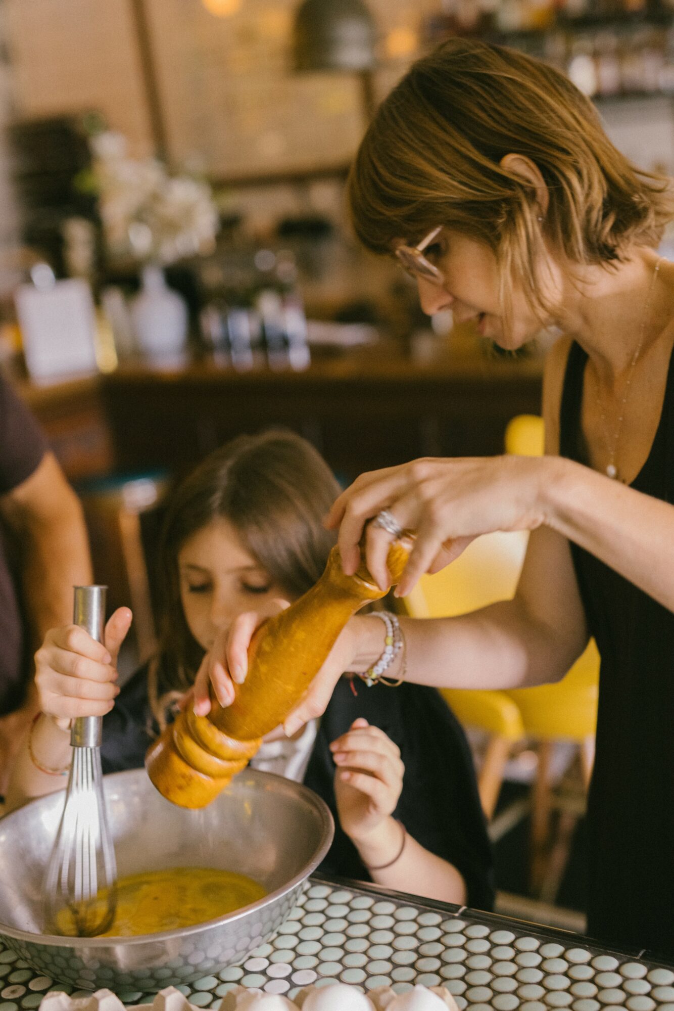 Woman pouring soup into a bowl for a young girl in a restaurant setting.