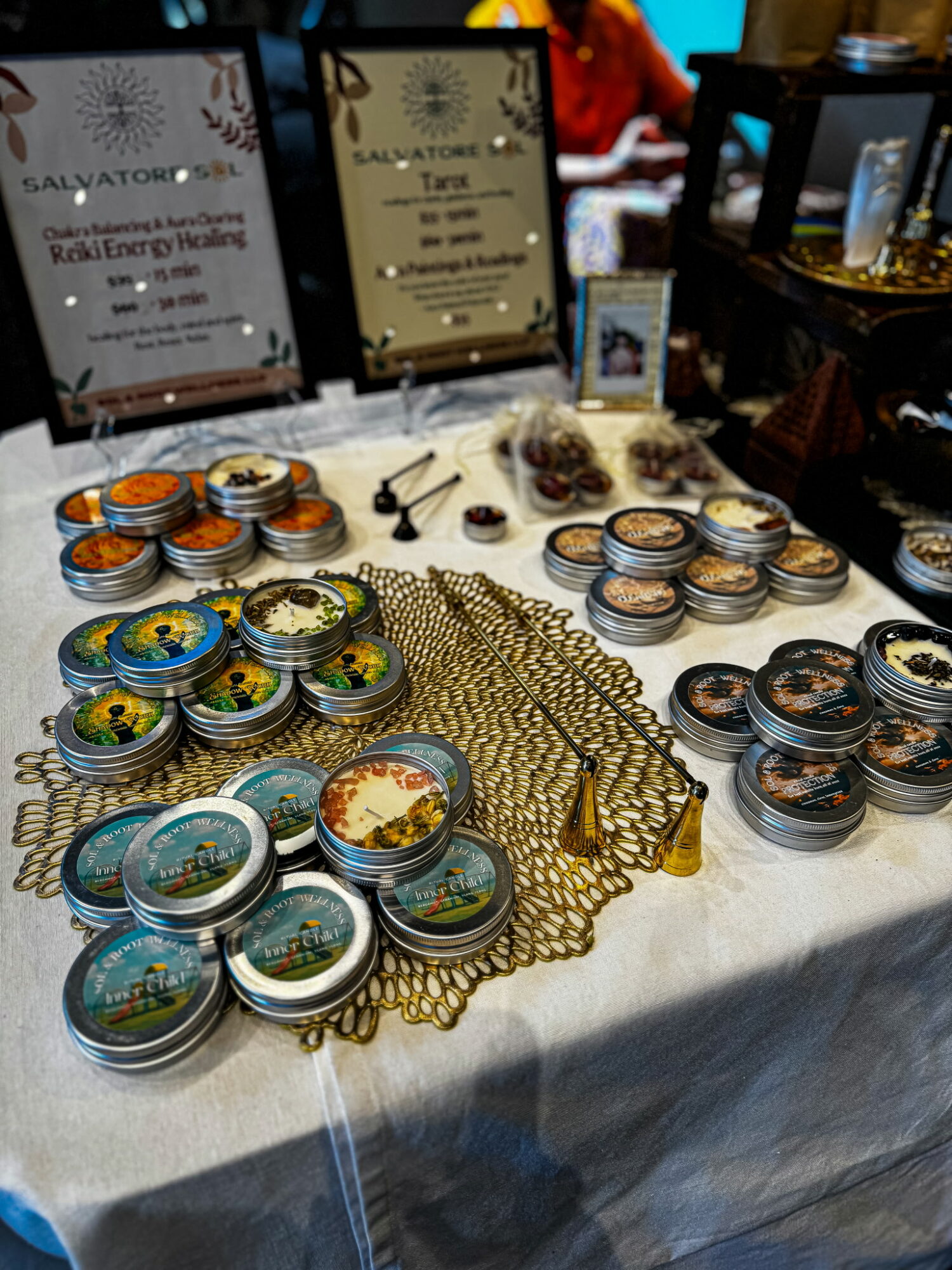 Table with small containers, jewelry, and signs, with blurred background of people and objects.