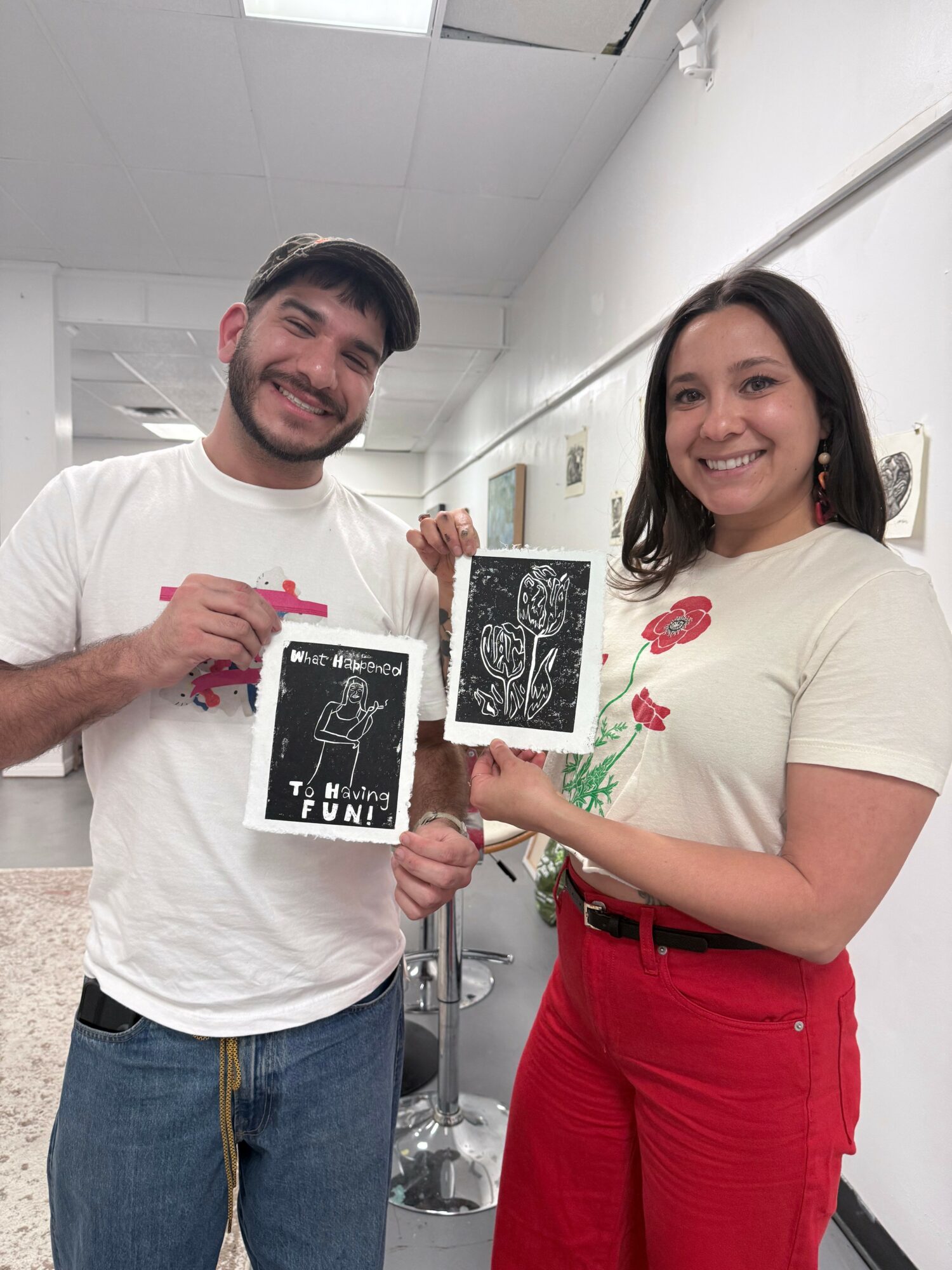 Two people smiling and holding ultrasound images in a clinical setting.