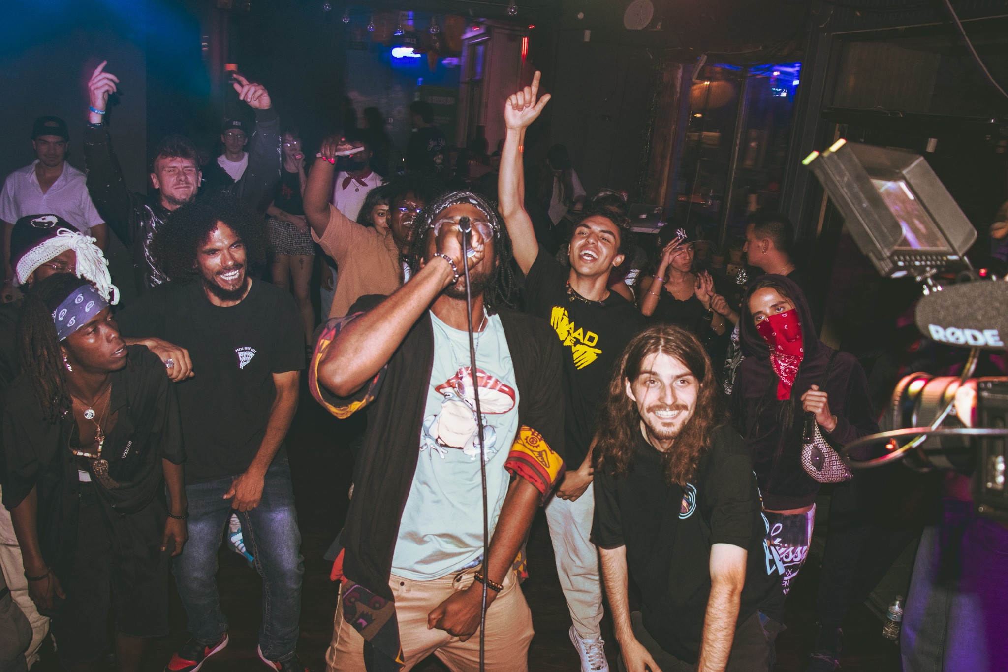 Group of people dancing and enjoying music in a dimly lit club with colorful lights.