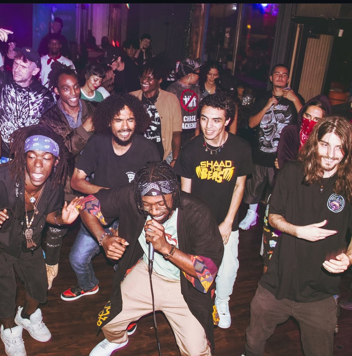 Group of people dancing and enjoying music in a lively indoor setting.