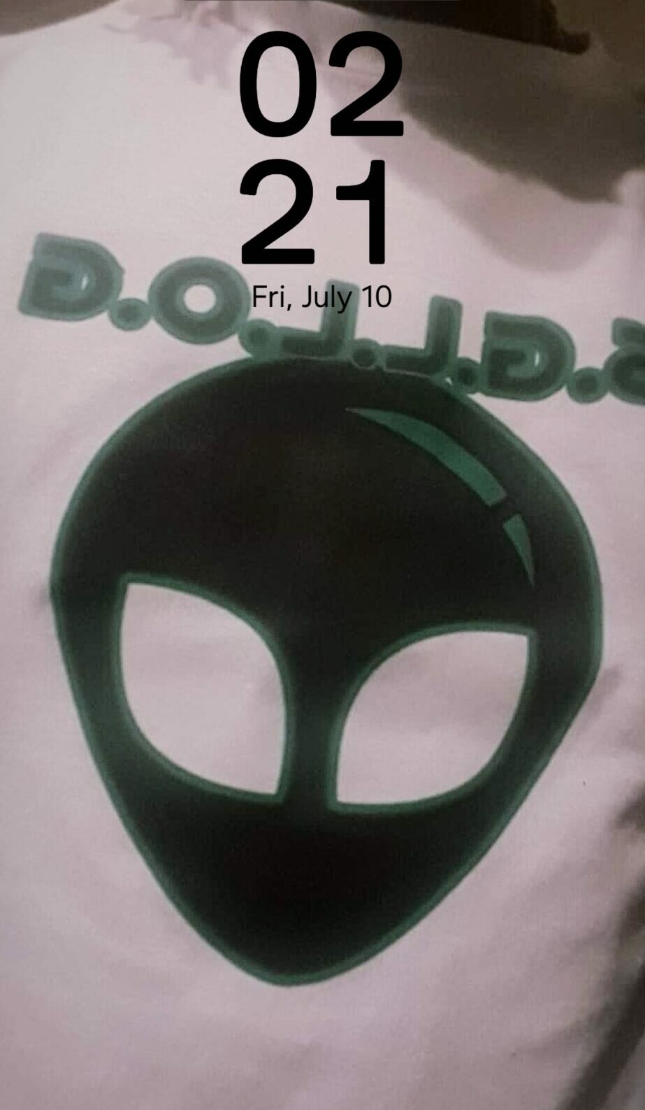 Alien mask with large eye holes on a white surface, digital clock showing 02:21, date July 10, Friday.