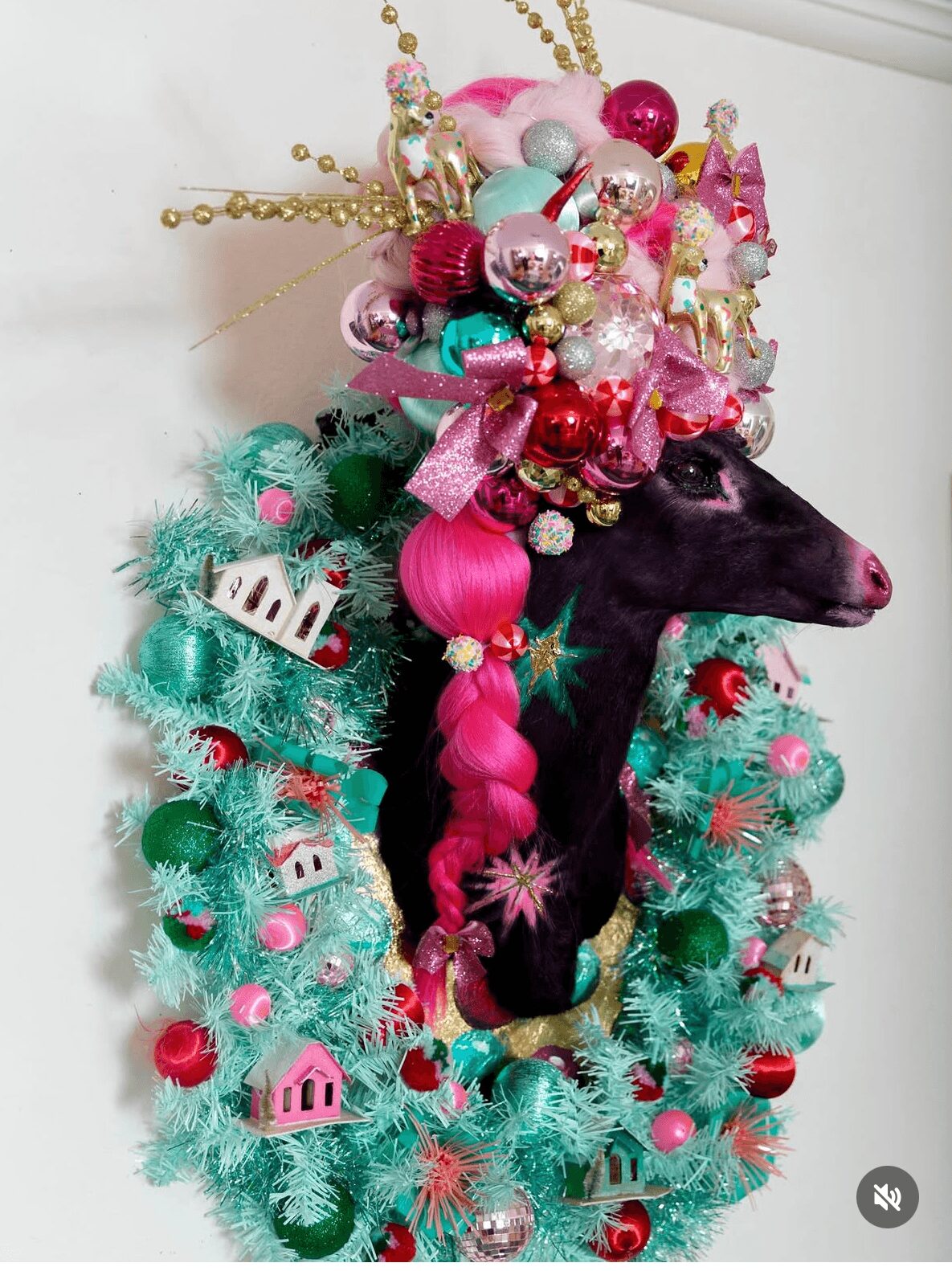 Decorated black horse head with pink and gold ornaments, surrounded by a green Christmas wreath with pink and white decorations.