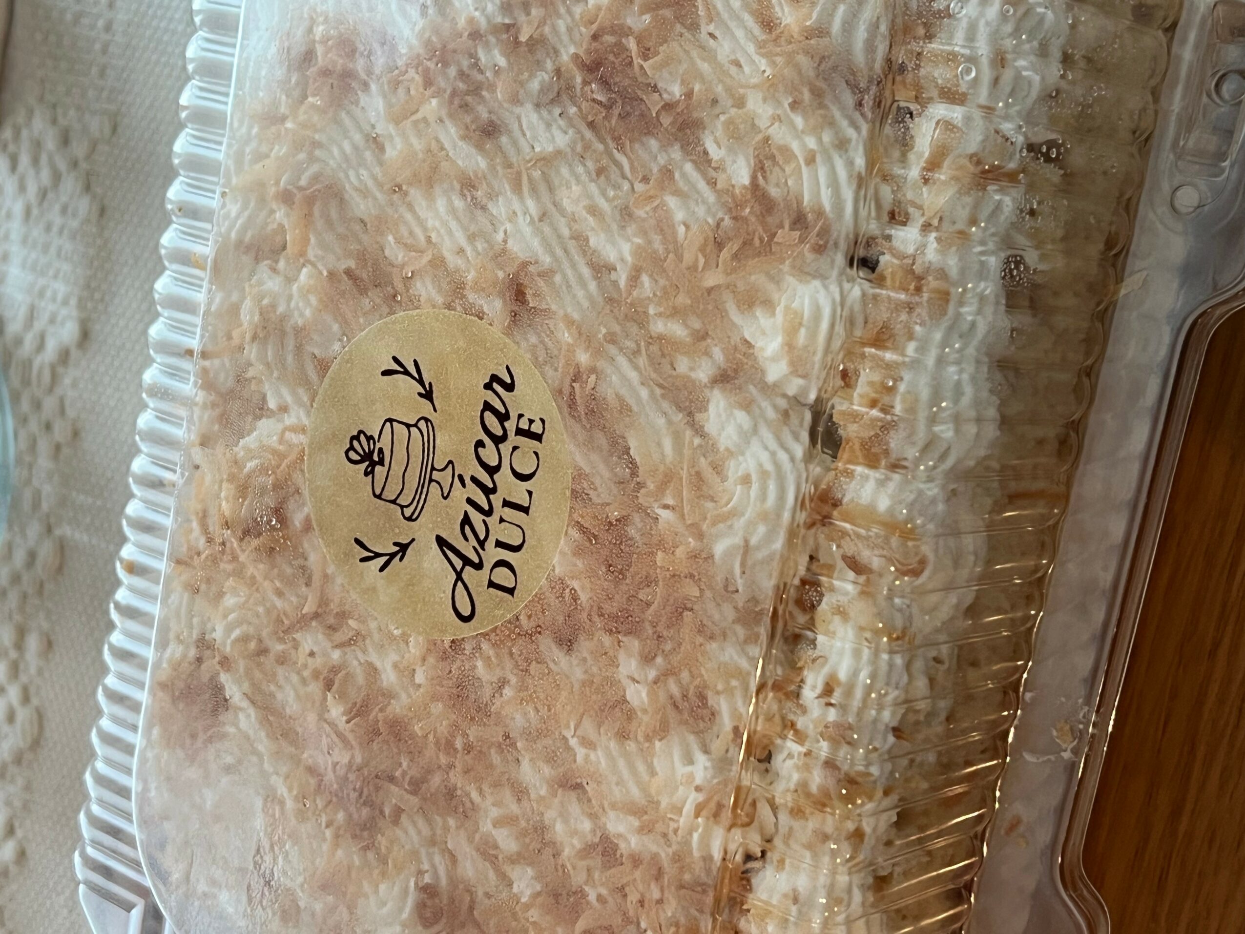 A cake with a label that reads 'Dulce Dulce' and a drawing of a cake, placed on a clear plastic container.