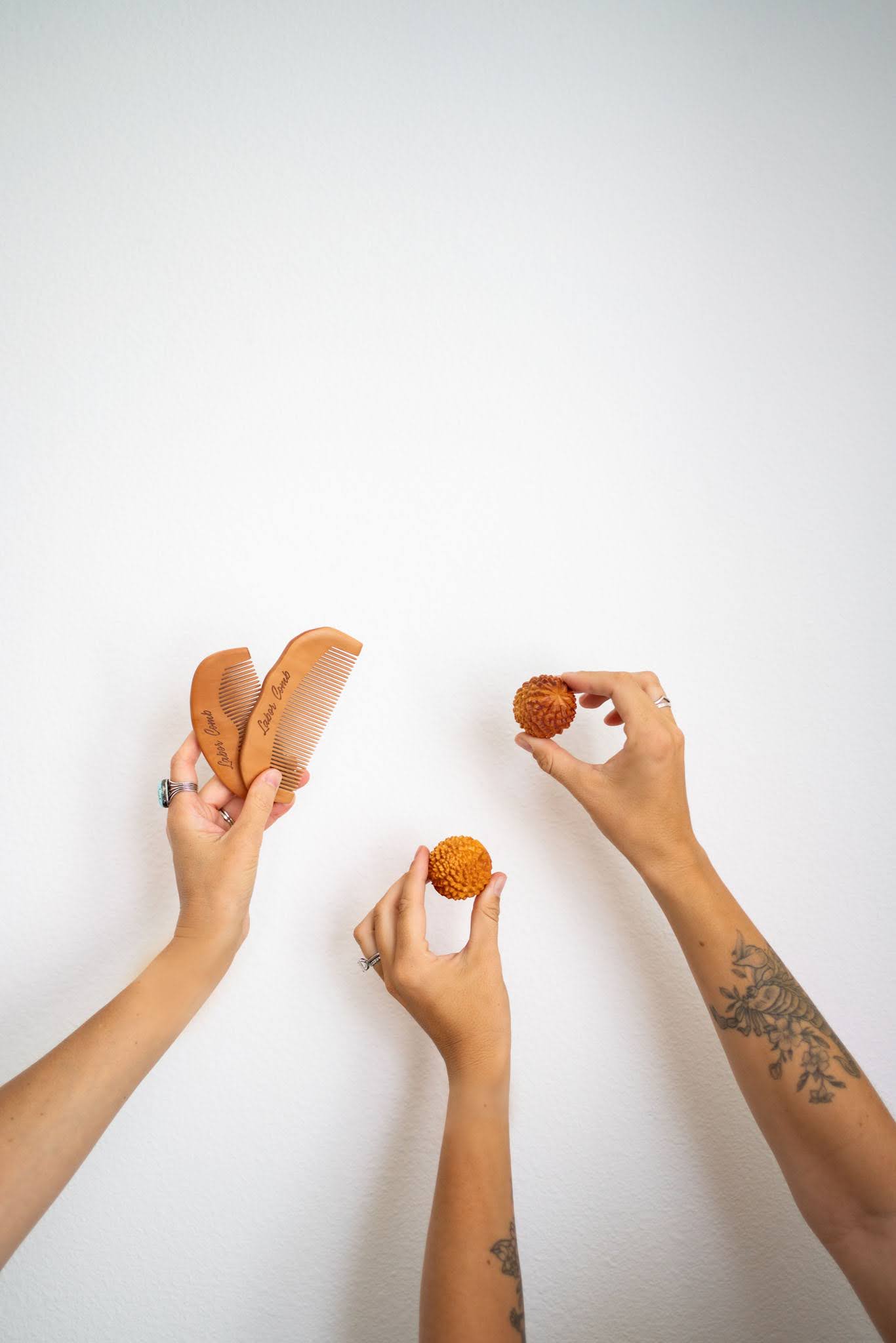 Two hands holding cupcakes and a third hand holding a hot dog on a white background.