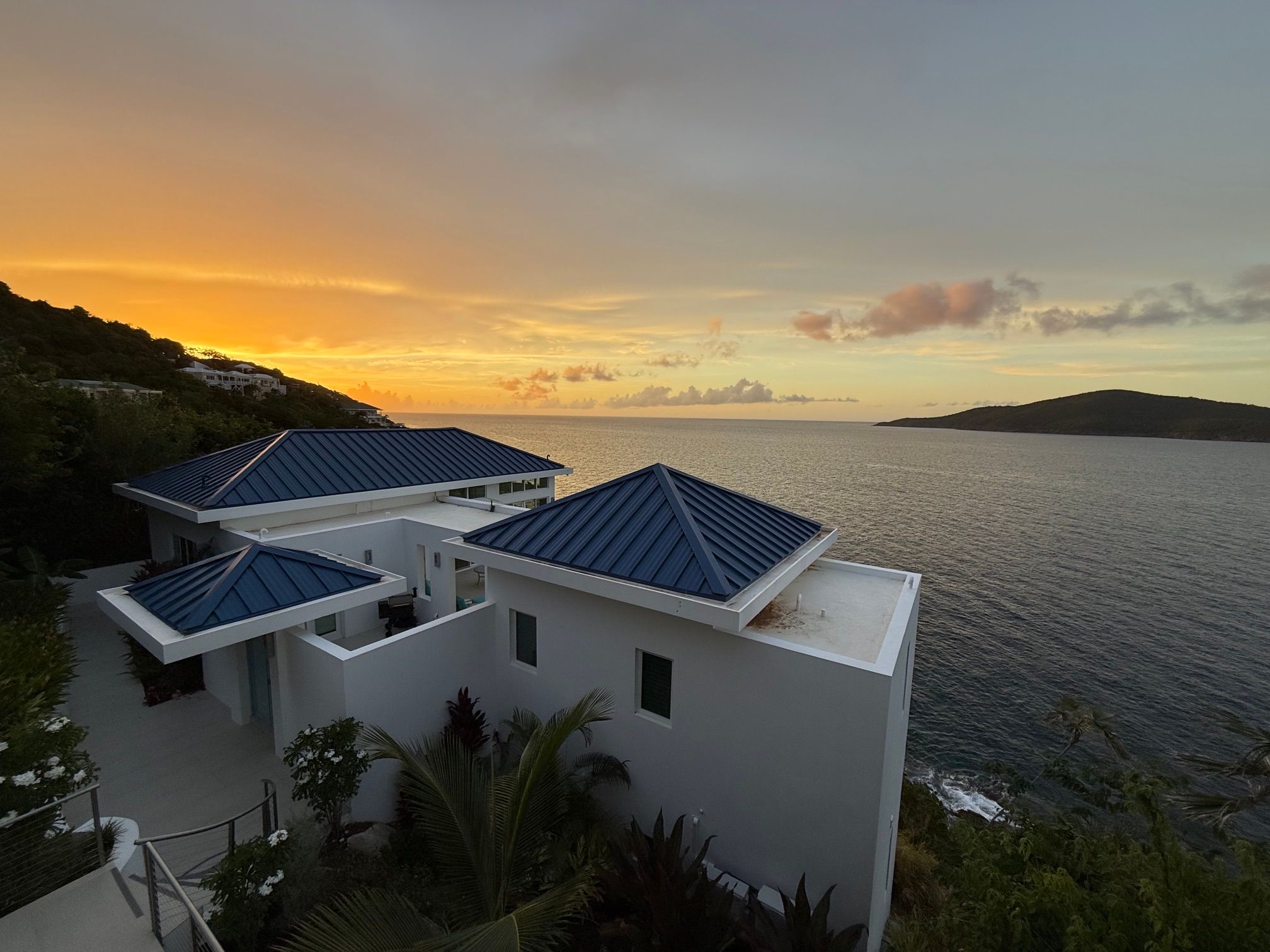 Upside-down view of a modern house with a swimming pool at sunset, overlooking a body of water and hills.
