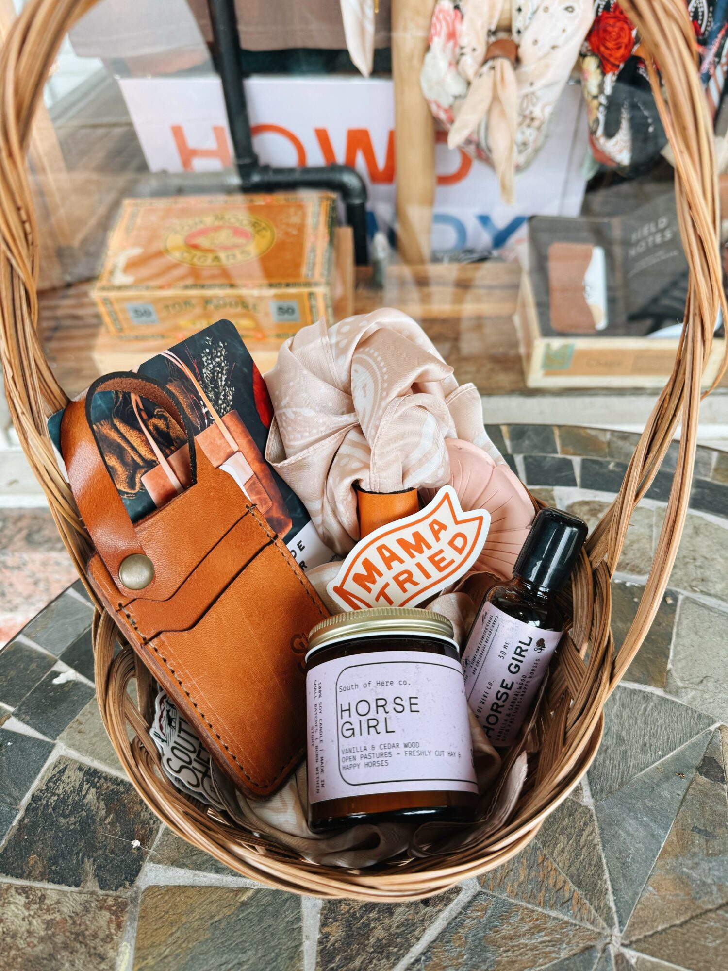 Basket containing a leather cardholder, a scrunchie, a small bottle, and a jar labeled 'Horse Girl'.