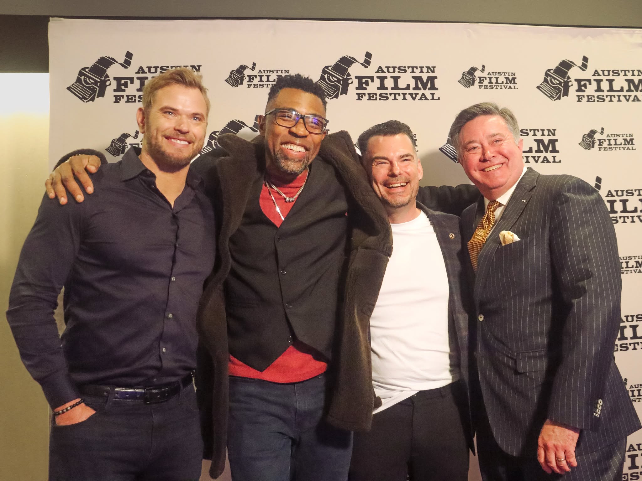 Four men standing together at Austin Film Festival, smiling, with a backdrop displaying event logos.