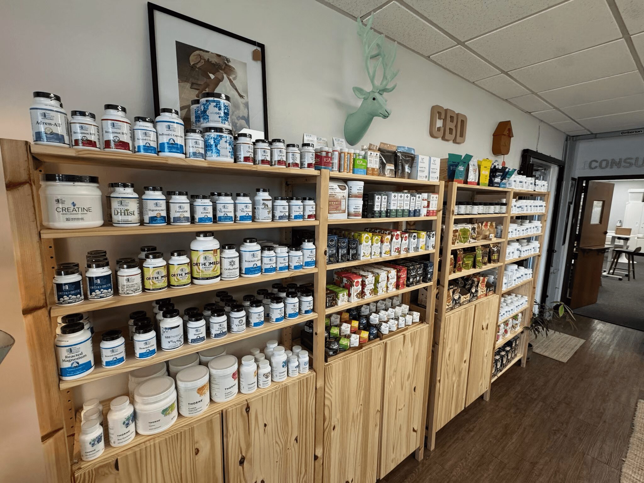 Shelves filled with various bottles and containers, a framed picture, and decorative items on the wall in a store or office.