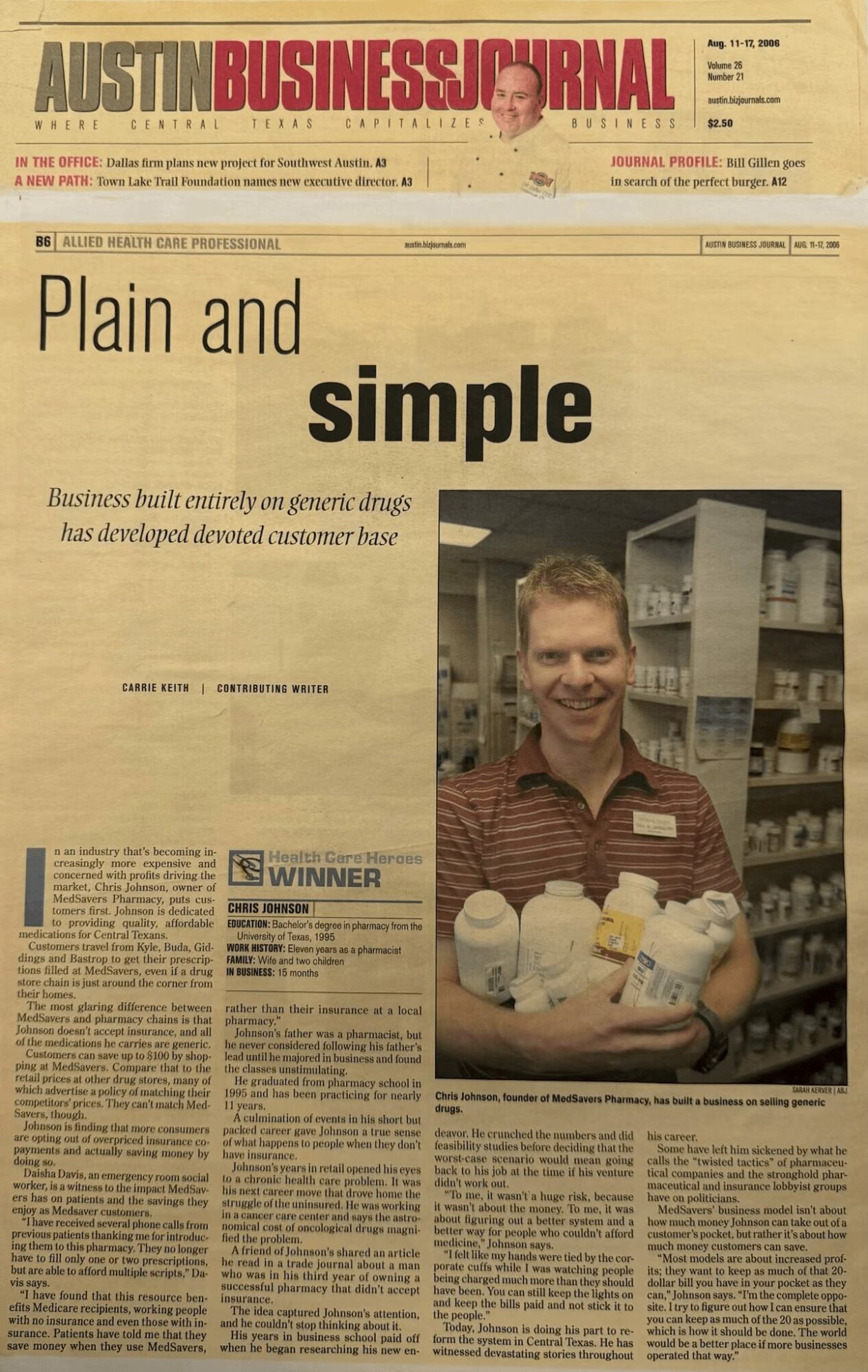 Man in a store holding a tray of packaged products, smiling, with shelves in the background, newspaper headline reads 'Plain and simple'.