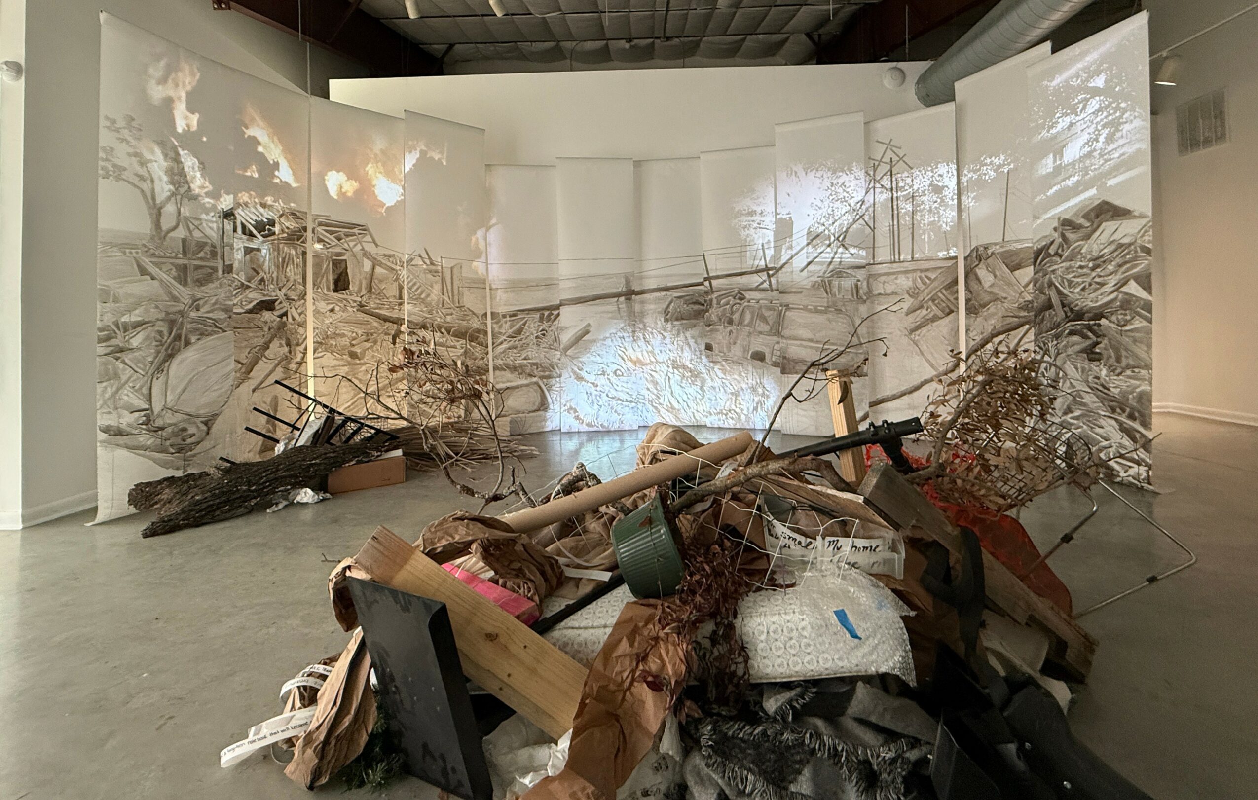 Indoor art installation with debris, broken wood, and scattered objects in a gallery space.