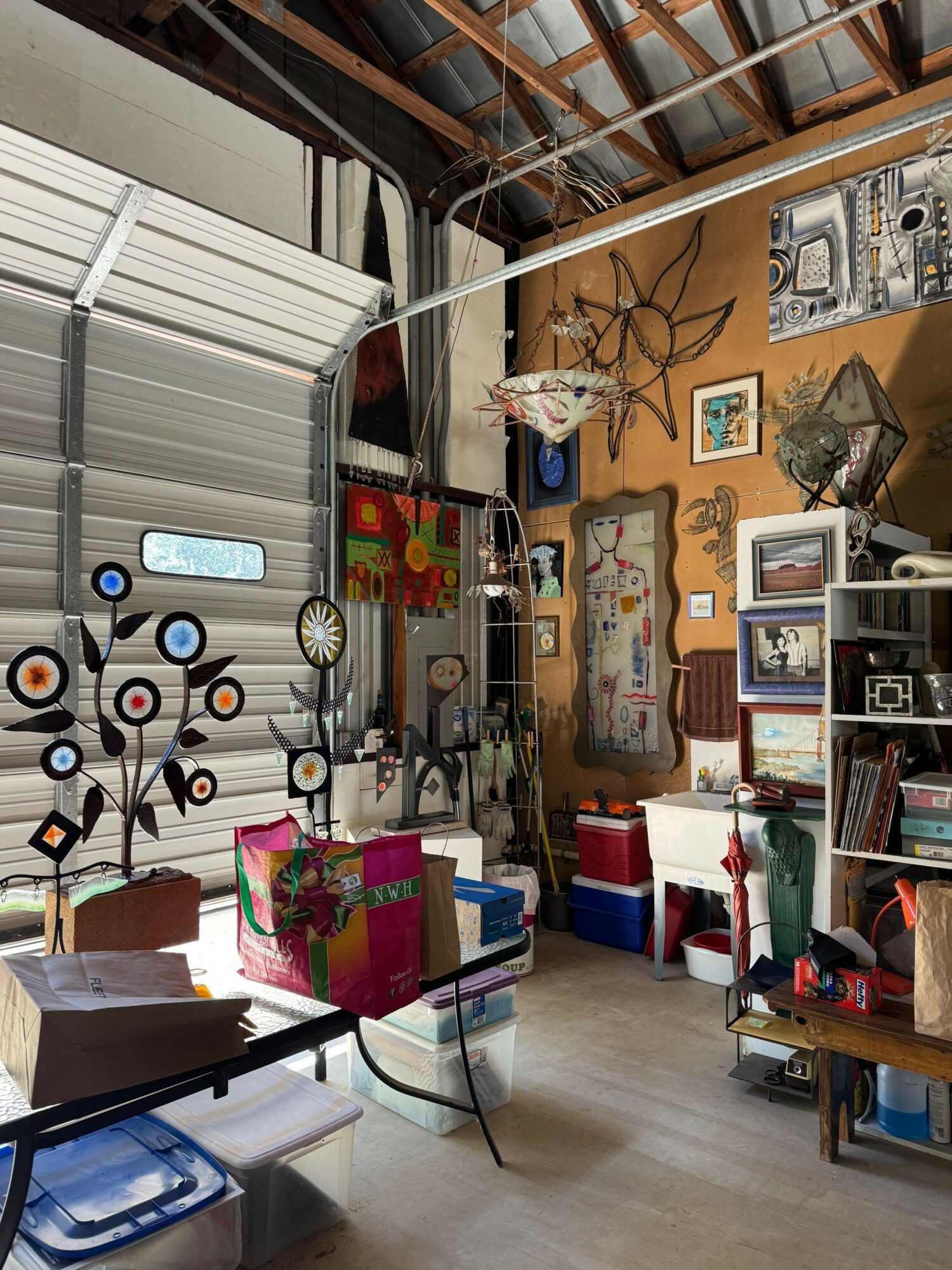 Room with shelves, artwork, and various objects, viewed from a tilted angle, with a glass table and chairs in the foreground.