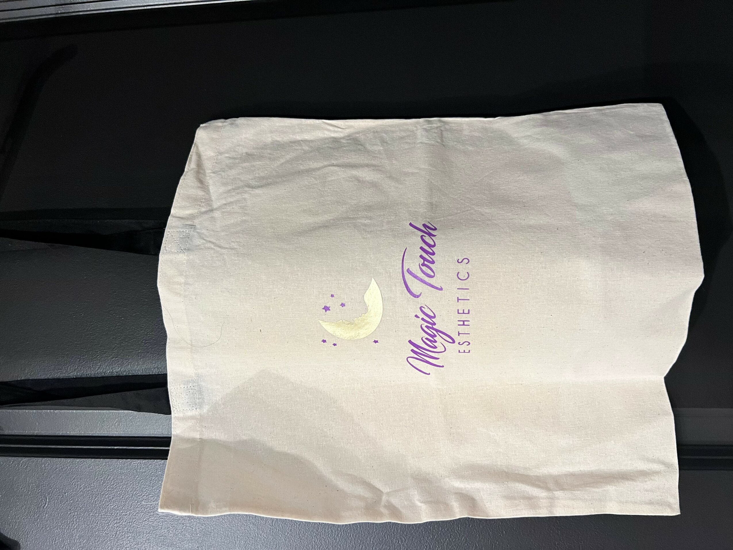 A white paper bag with purple and yellow logo and text, placed on a dark surface.