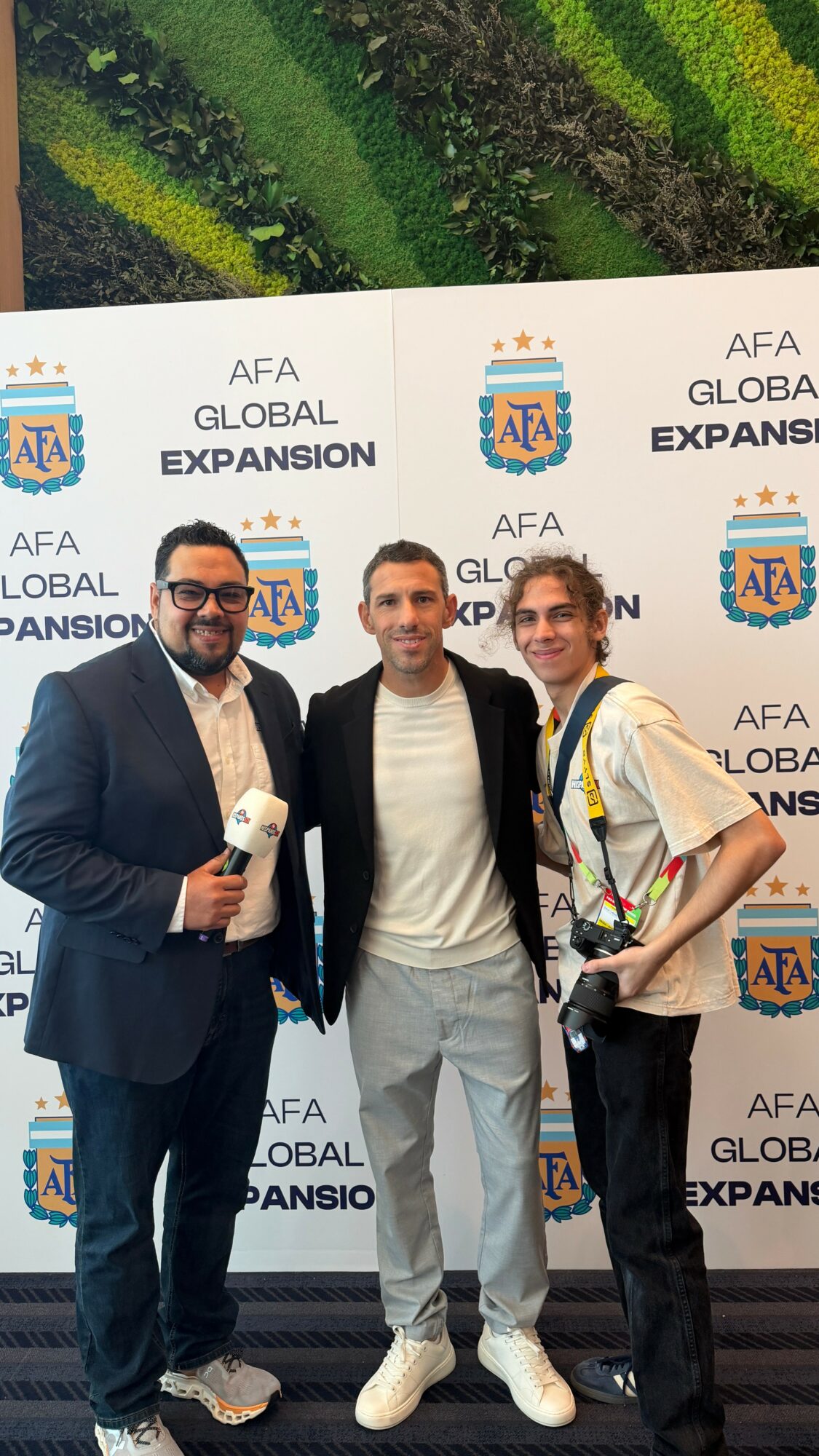 Three people standing in front of a backdrop with AFA Global Expansion logo, smiling, indoors.