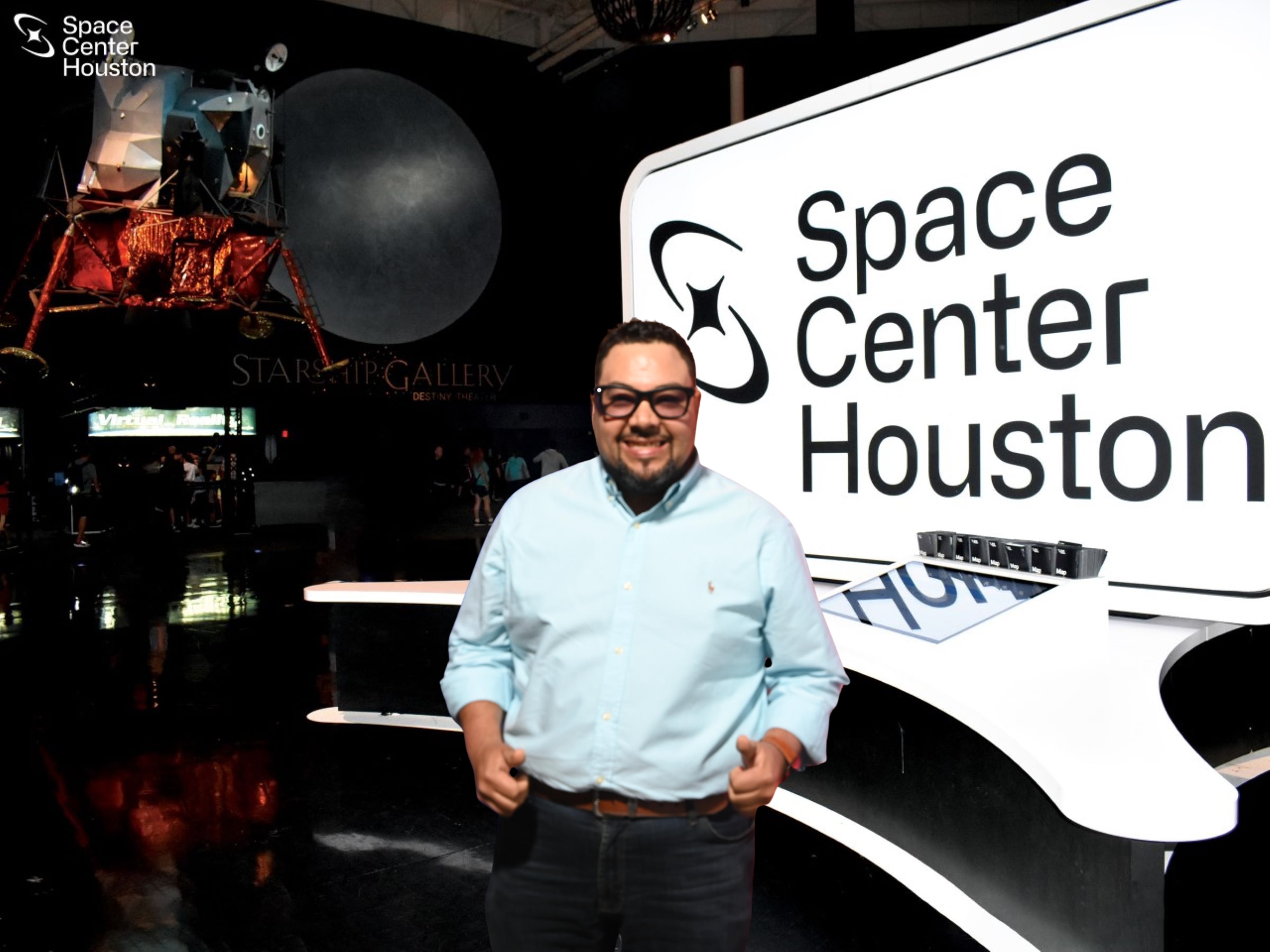 Man in light blue shirt standing in front of a large screen displaying 'Space Center Houston' logo.