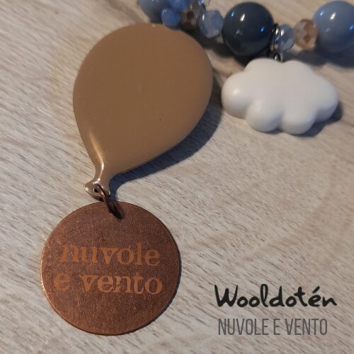 Beaded necklace with a brown circular pendant and cloud-shaped charm on a wooden surface.