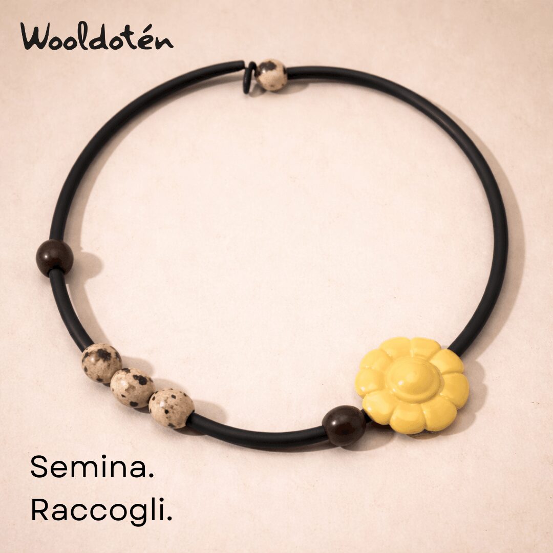Black necklace with yellow flower pendant and beige beads, on a light background.