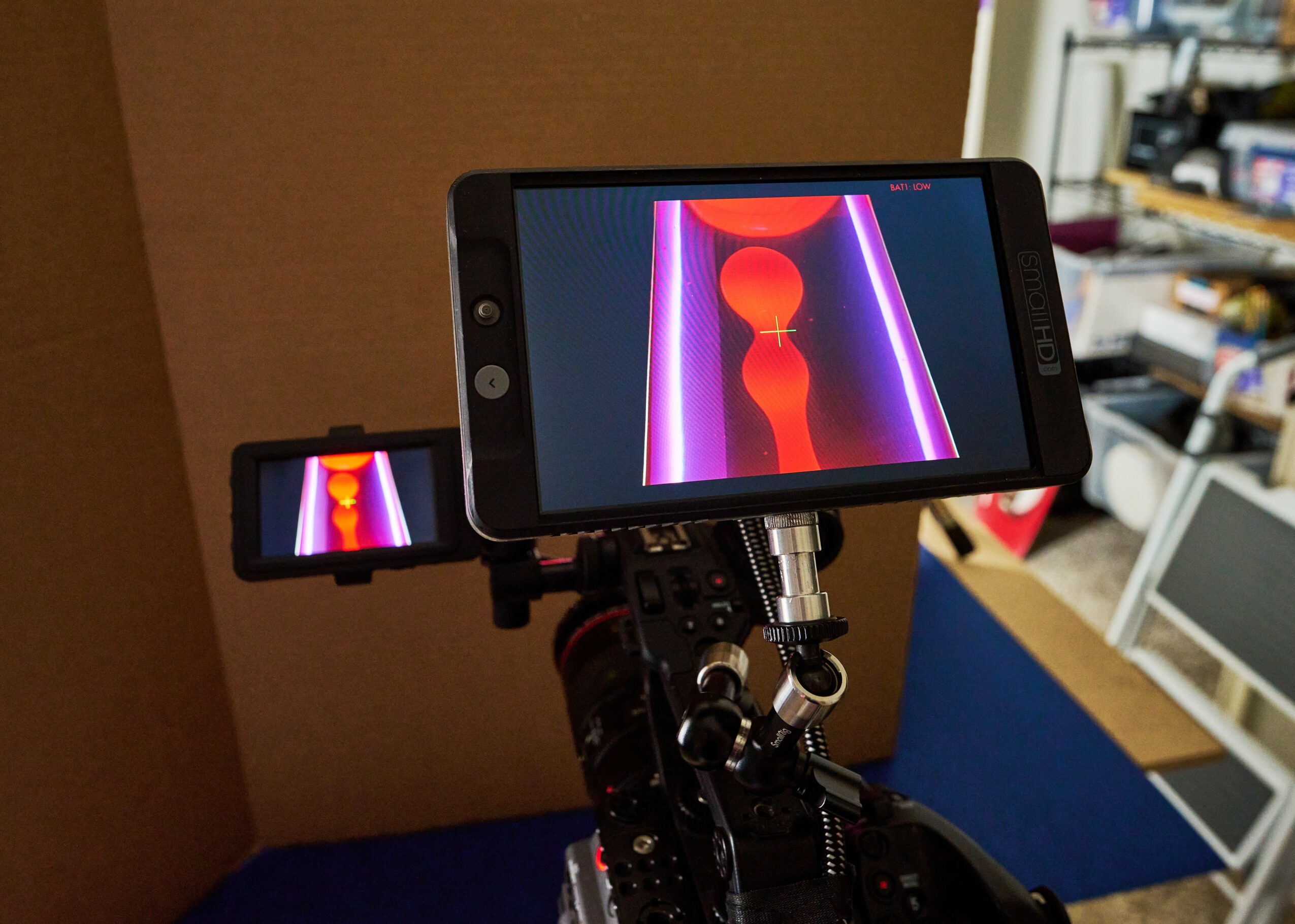 Smartphone mounted on a rig displaying a colorful abstract pattern with vertical lines and circles.
