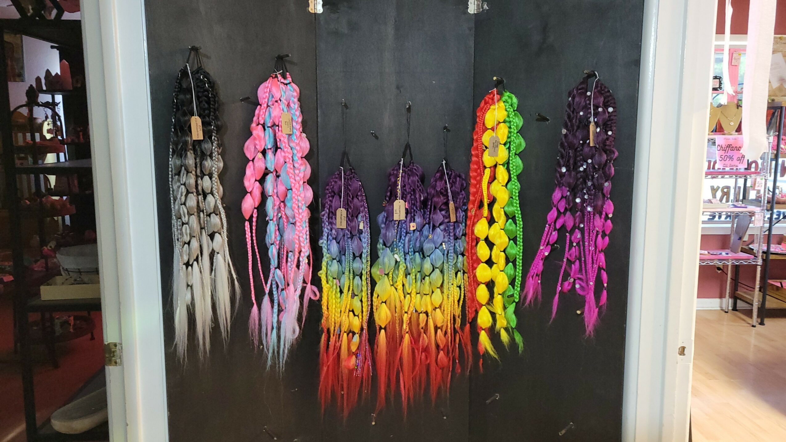 Display of colorful beaded necklaces hanging on a black background, with a variety of colors and styles.