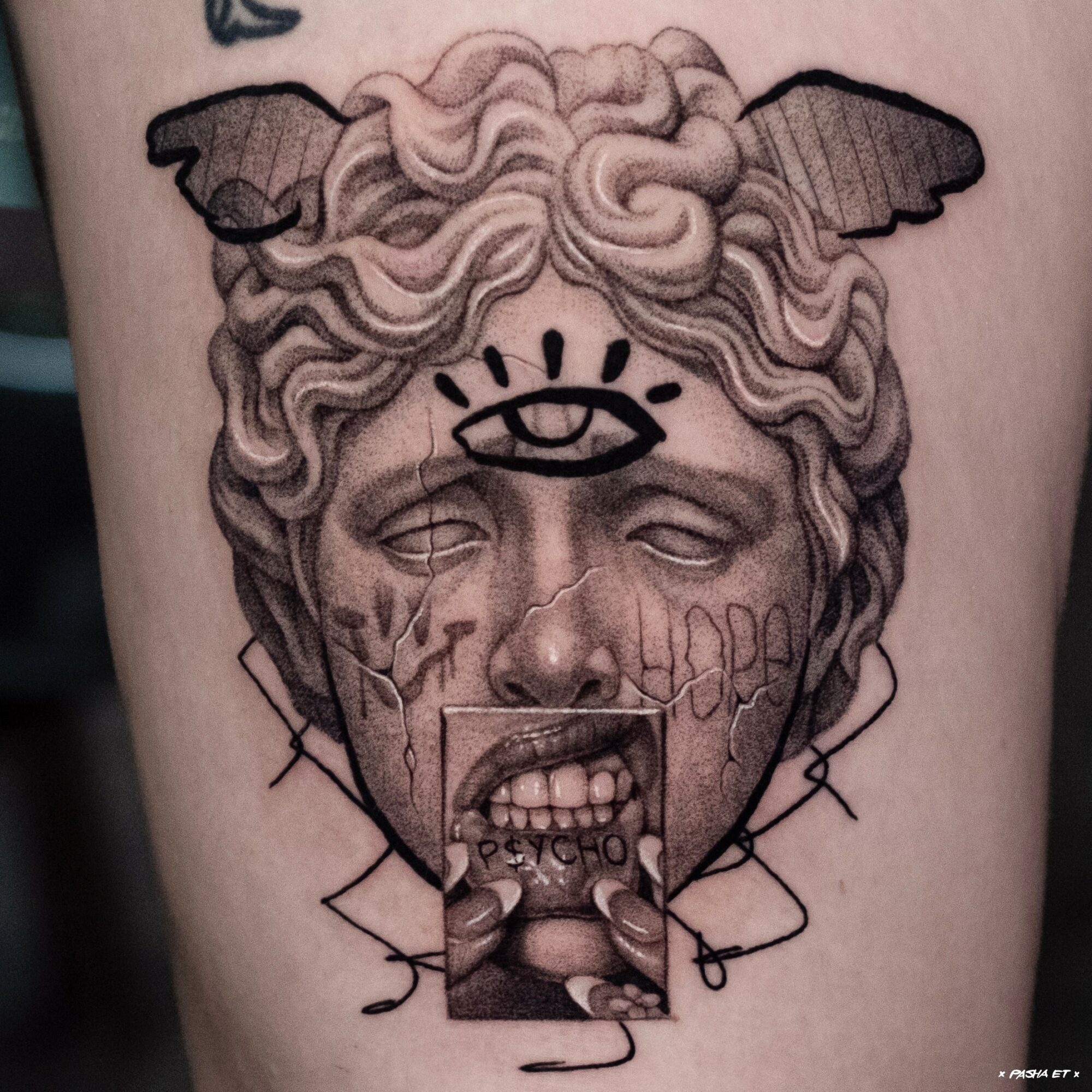 Tattoo of a classical sculpture head with animal ears, tears, and a photo inset on the face, with a chain design.
