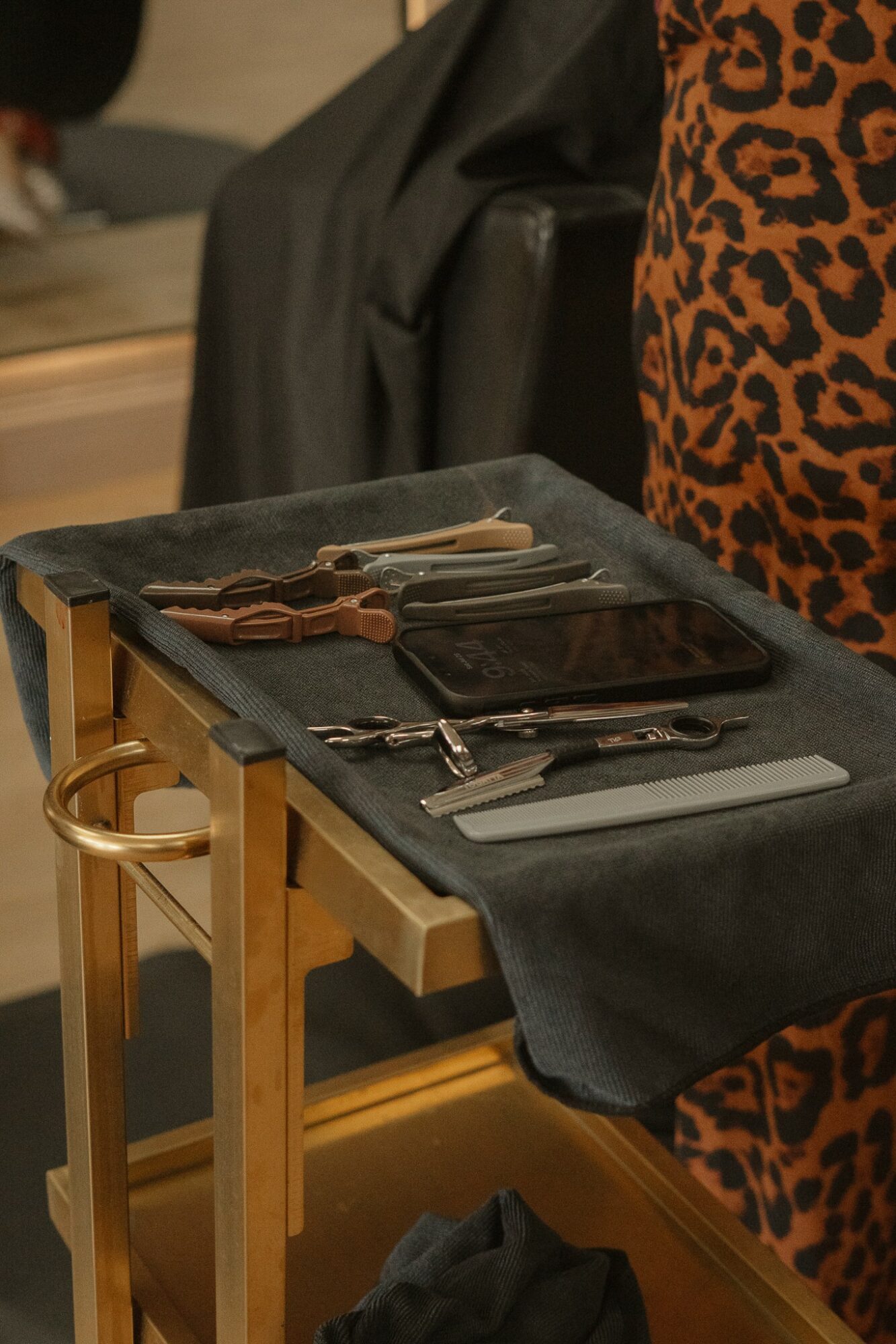 A table with cutlery, napkins, and a black cloth, set for a meal, with a person in animal print clothing nearby.