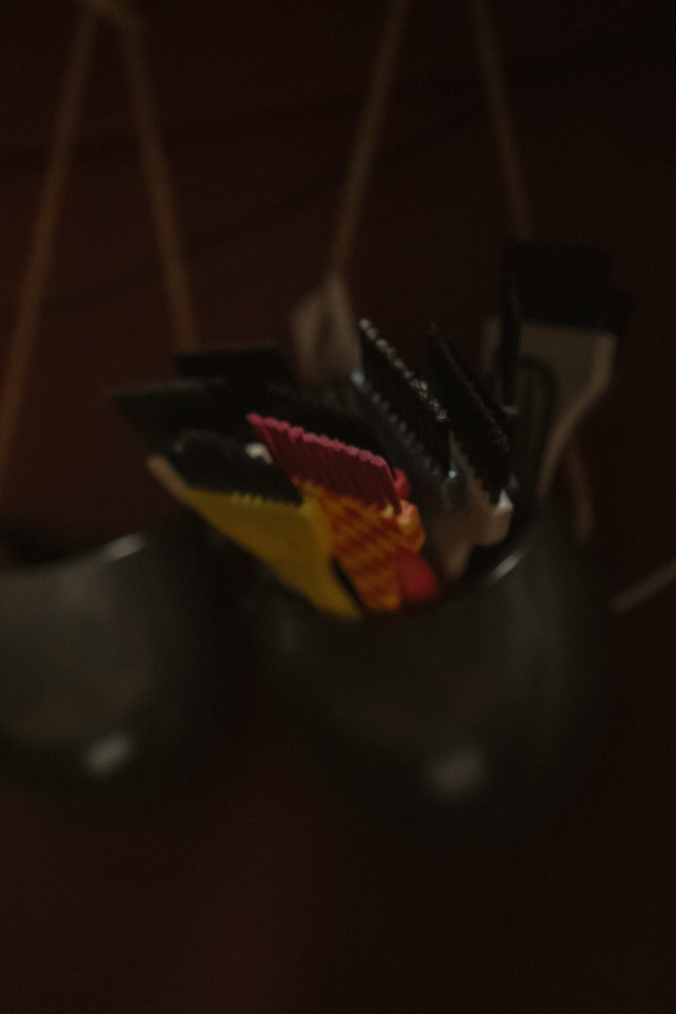 A black container holding colorful knitting or crochet tools and yarns, with a dark background.