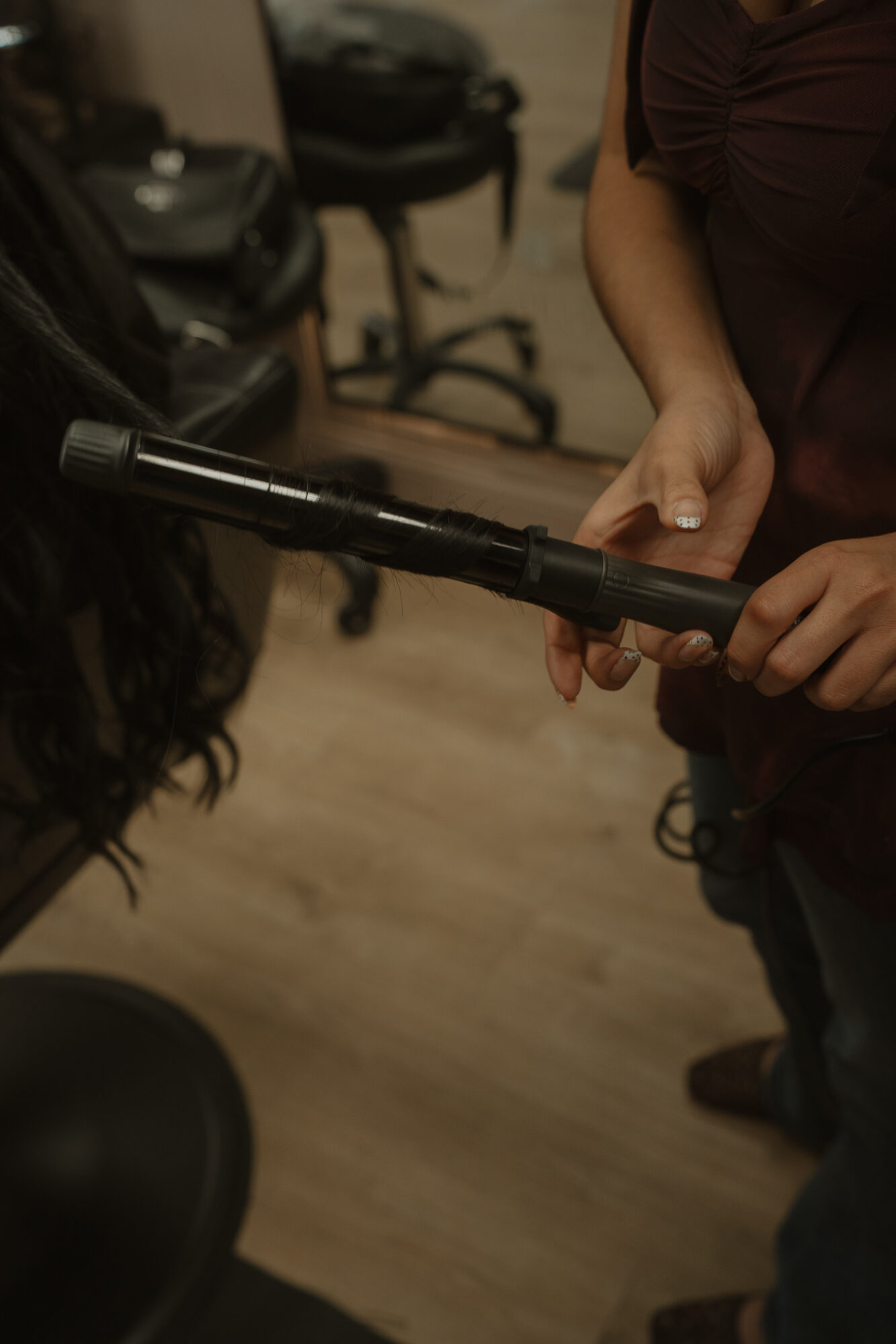 Two people exchanging a black cylindrical object in a room with chairs and a wooden floor.