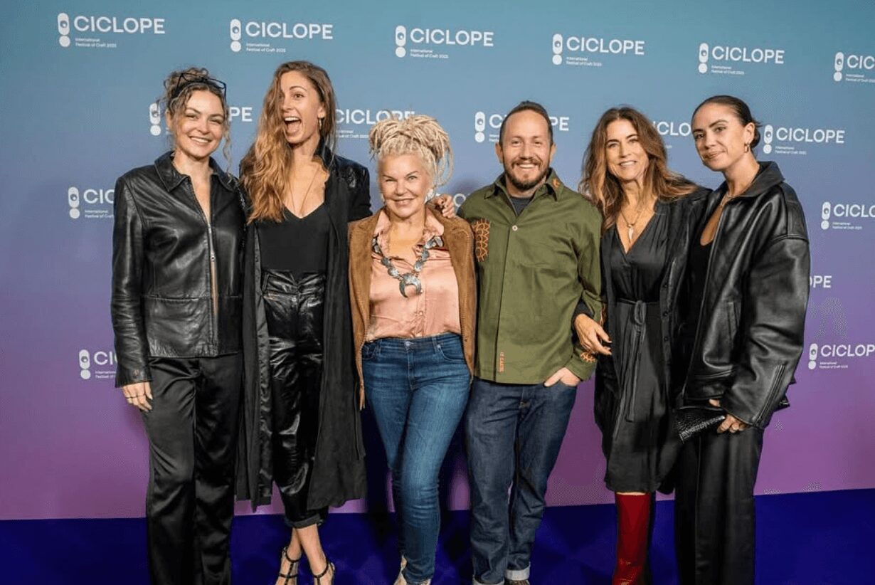Six people stand together in front of a blue backdrop with repeated 'CICLOPE' logos, smiling and posing for the photo.