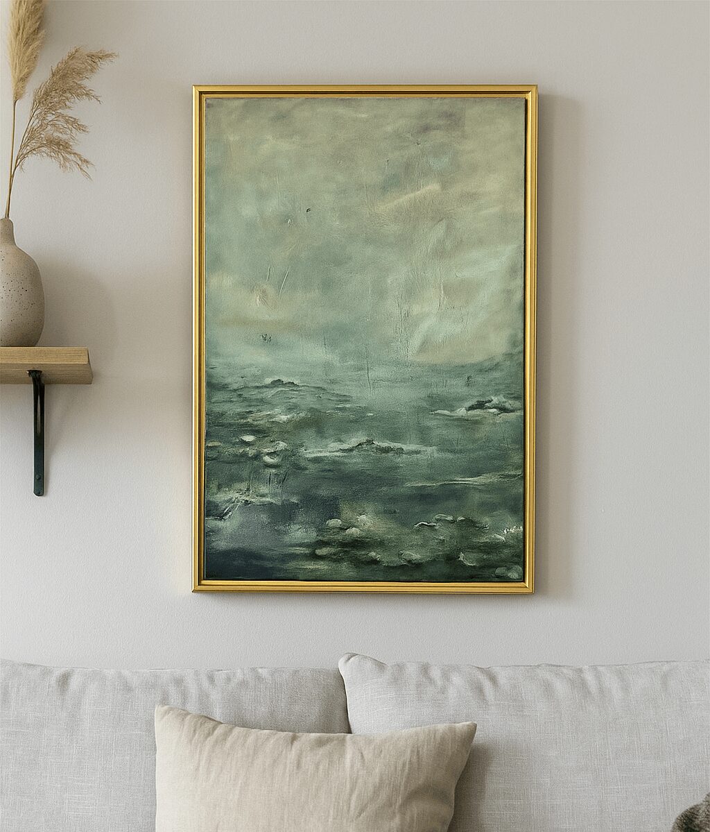 Framed abstract painting of a seascape hangs above a light-colored sofa with a pillow, on a white wall.