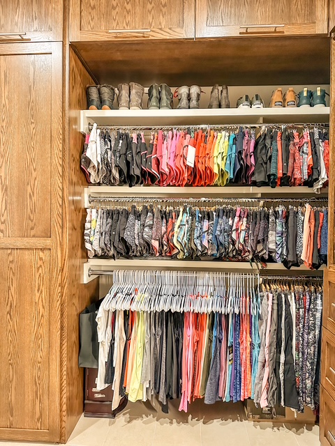 Closet with shelves of shoes and hanging clothes, wooden cabinets on the side, organized clothing and footwear.