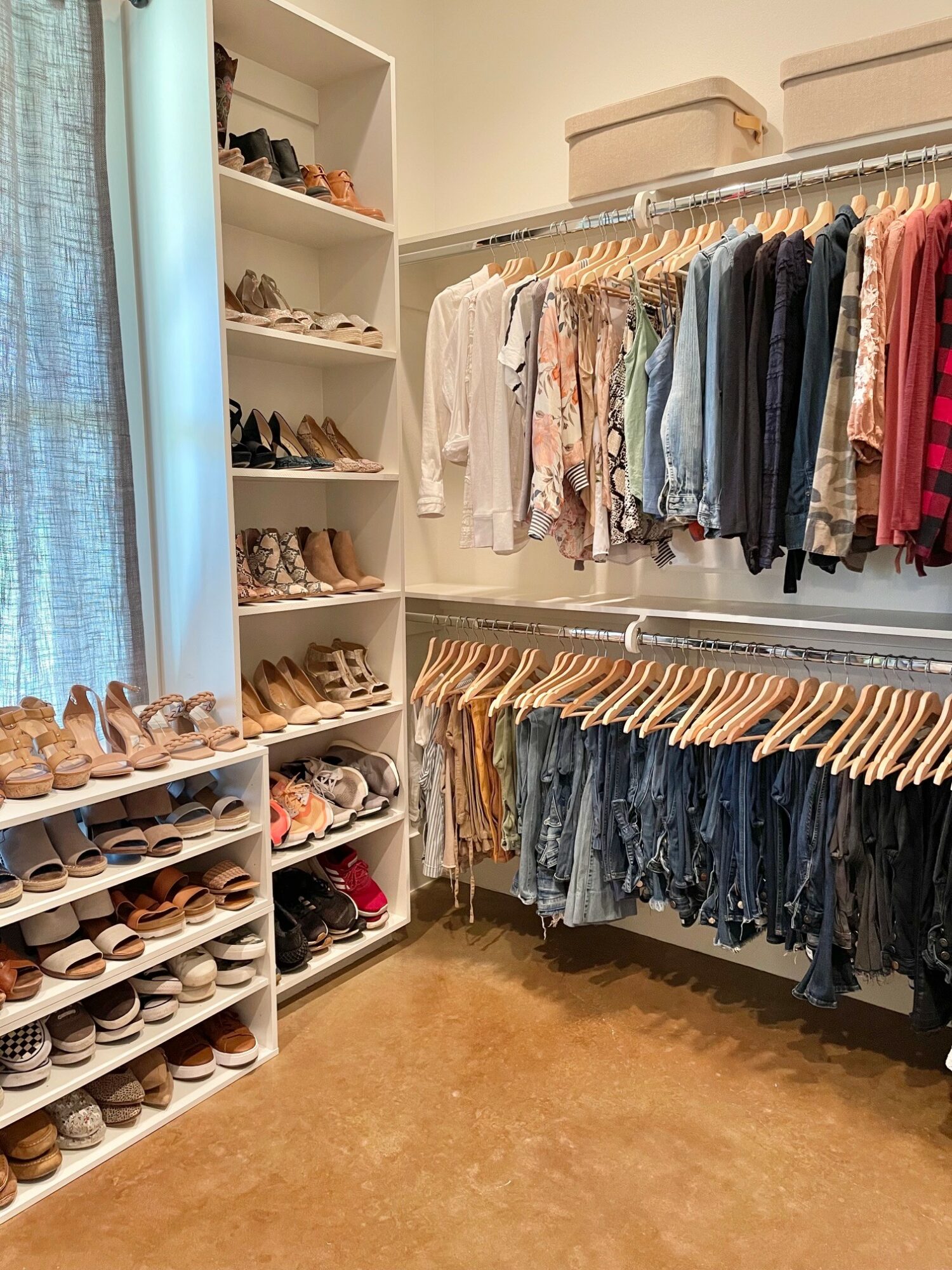 Closet with shoes on shelves and clothes hanging on racks, organized by type and color.