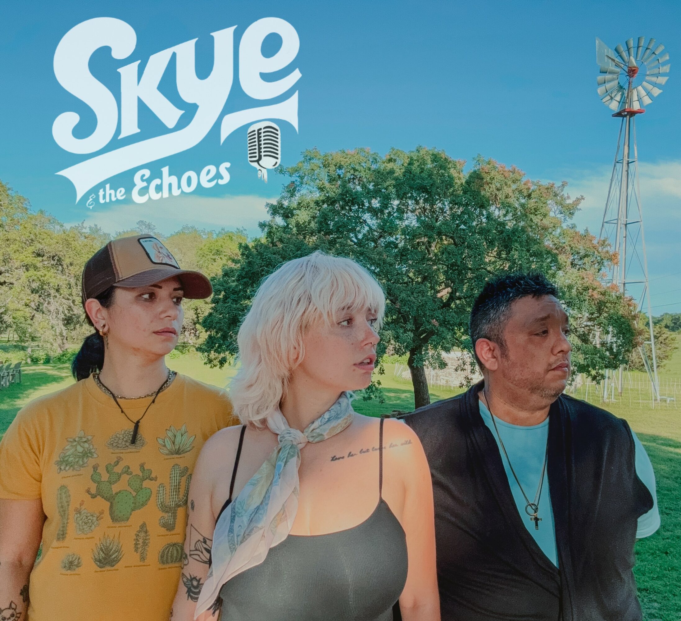 Three people standing outdoors with trees and a windmill in the background, under a blue sky.
