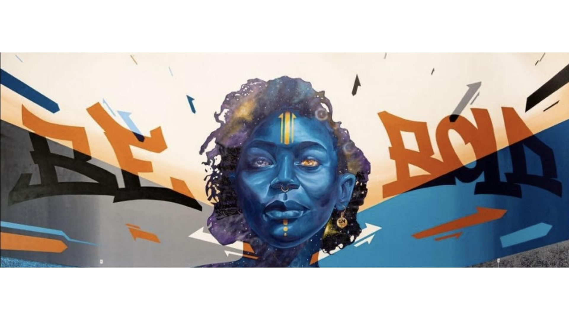 Graffiti-style mural of a blue-skinned woman with curly hair and gold face markings, surrounded by abstract shapes and colors.